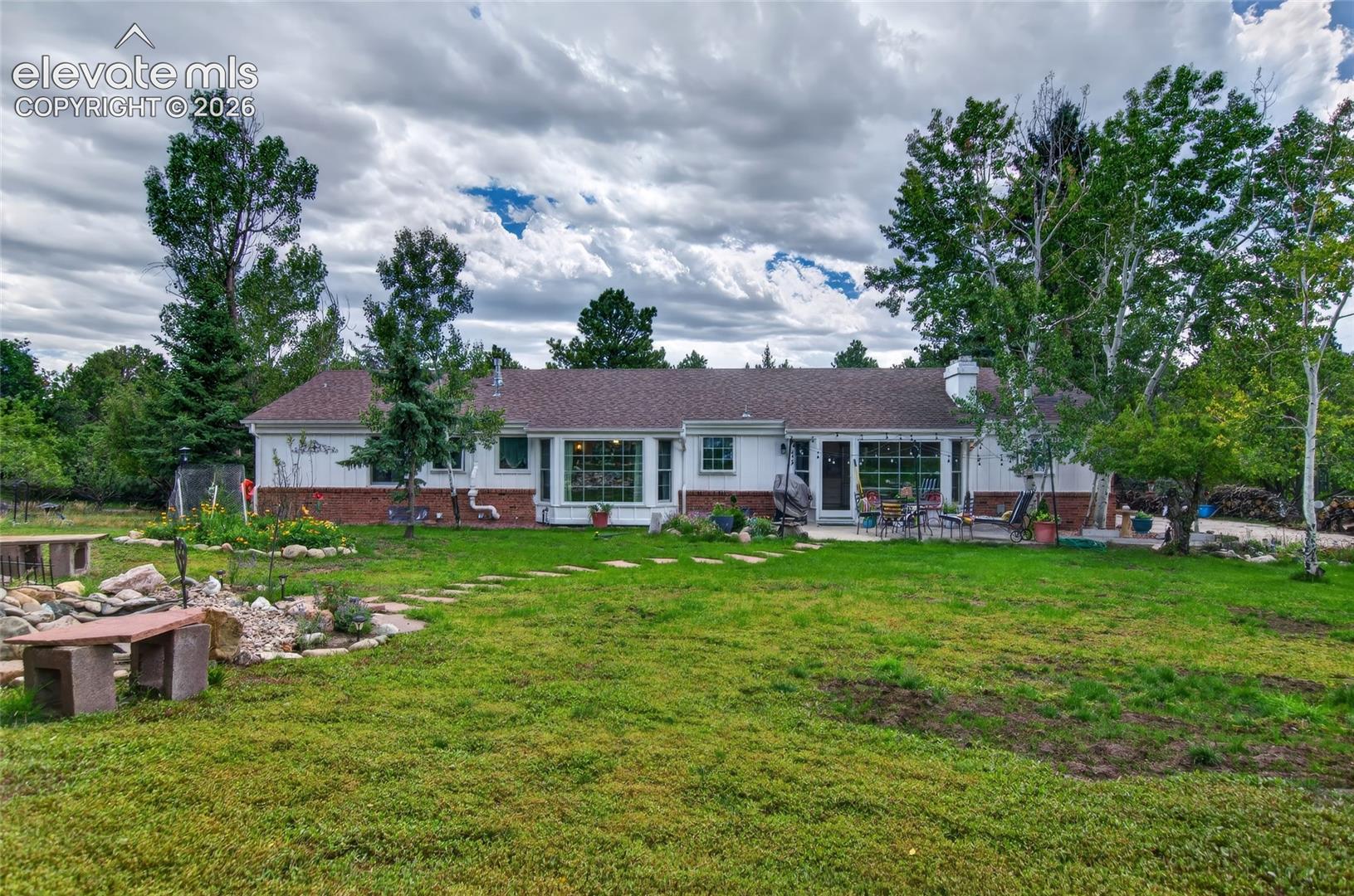 Expansive lawn with a stone pathway, mature trees, and a ground-level patio