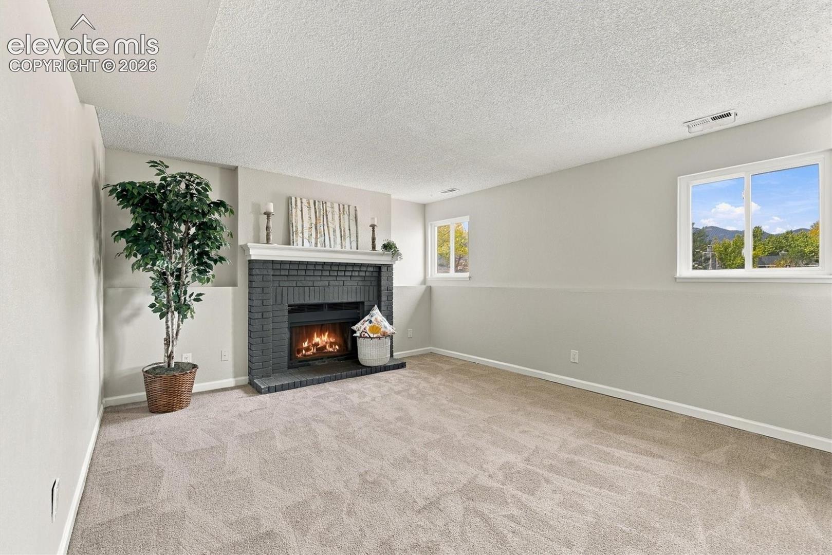 Brick fireplace with a decorative mantel, neutral wall-to-wall carpeting, and large sliding windows