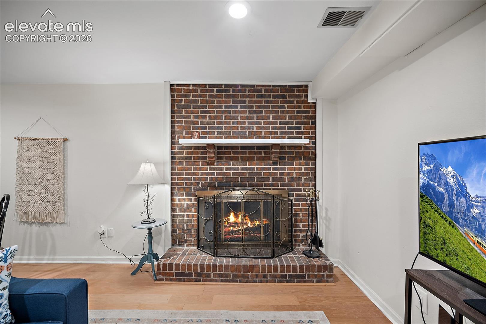 Floor-to-ceiling brick fireplace surround featuring a raised brick hearth and a prominent wooden mantel