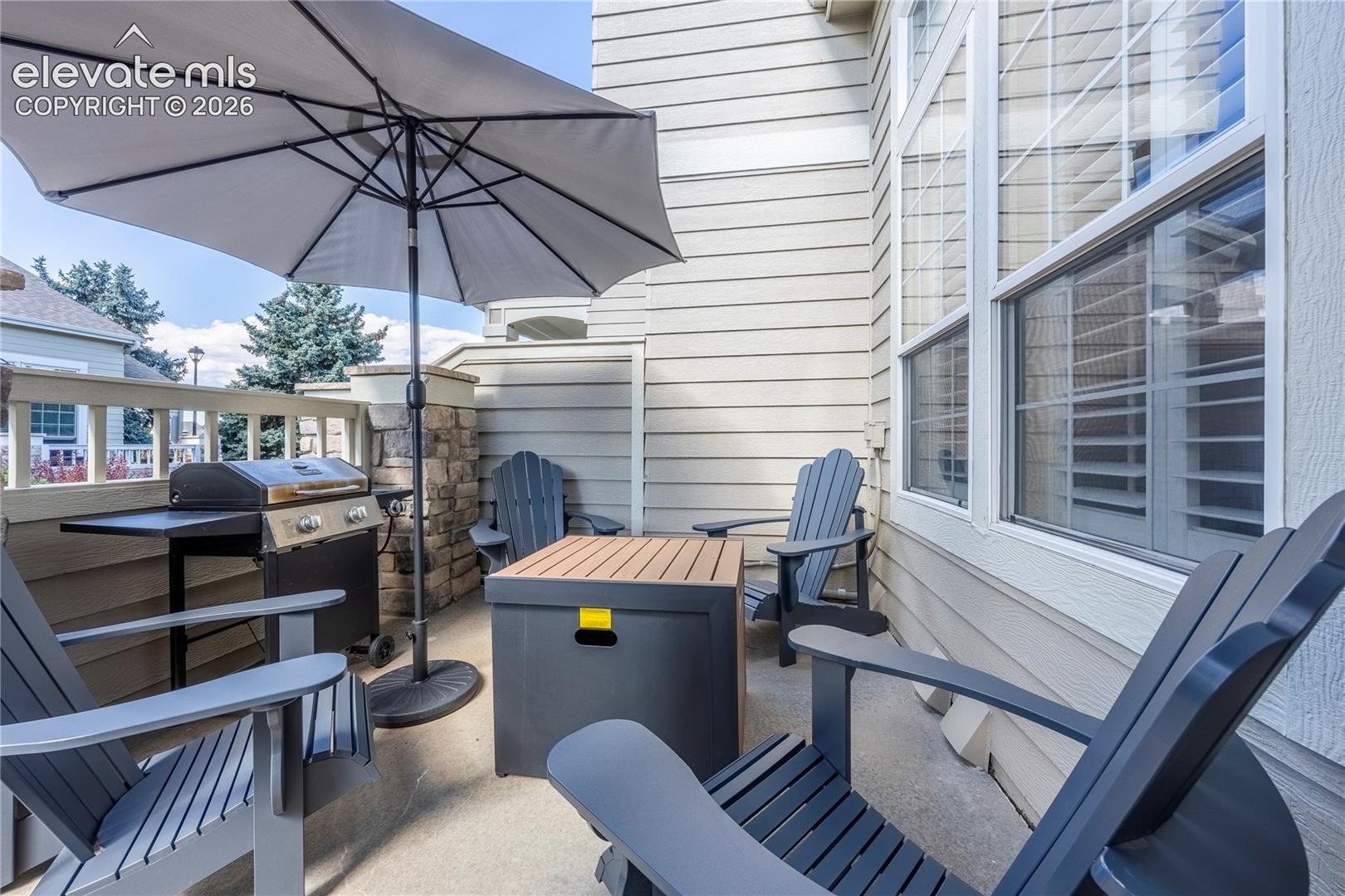 Private patio featuring horizontal lap siding, stone-accented pillar, concrete flooring, and multi-pane windows