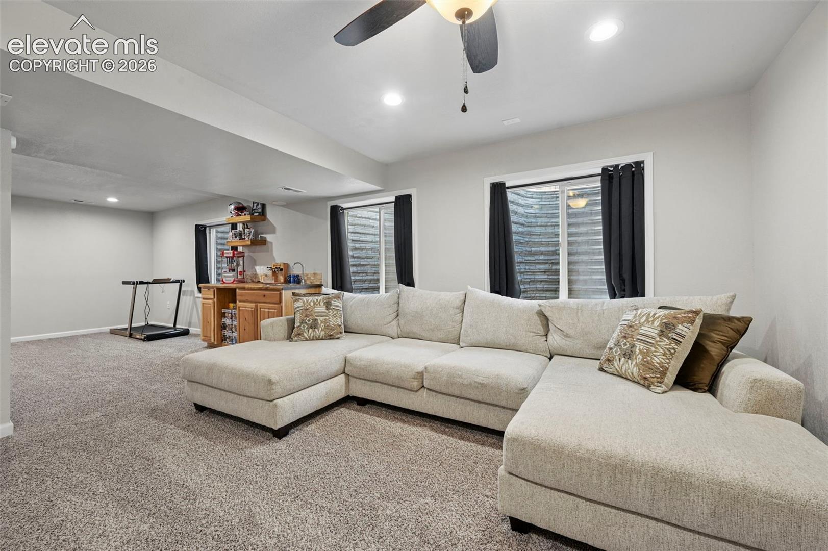 Recessed lighting, a ceiling fan, and carpeted flooring