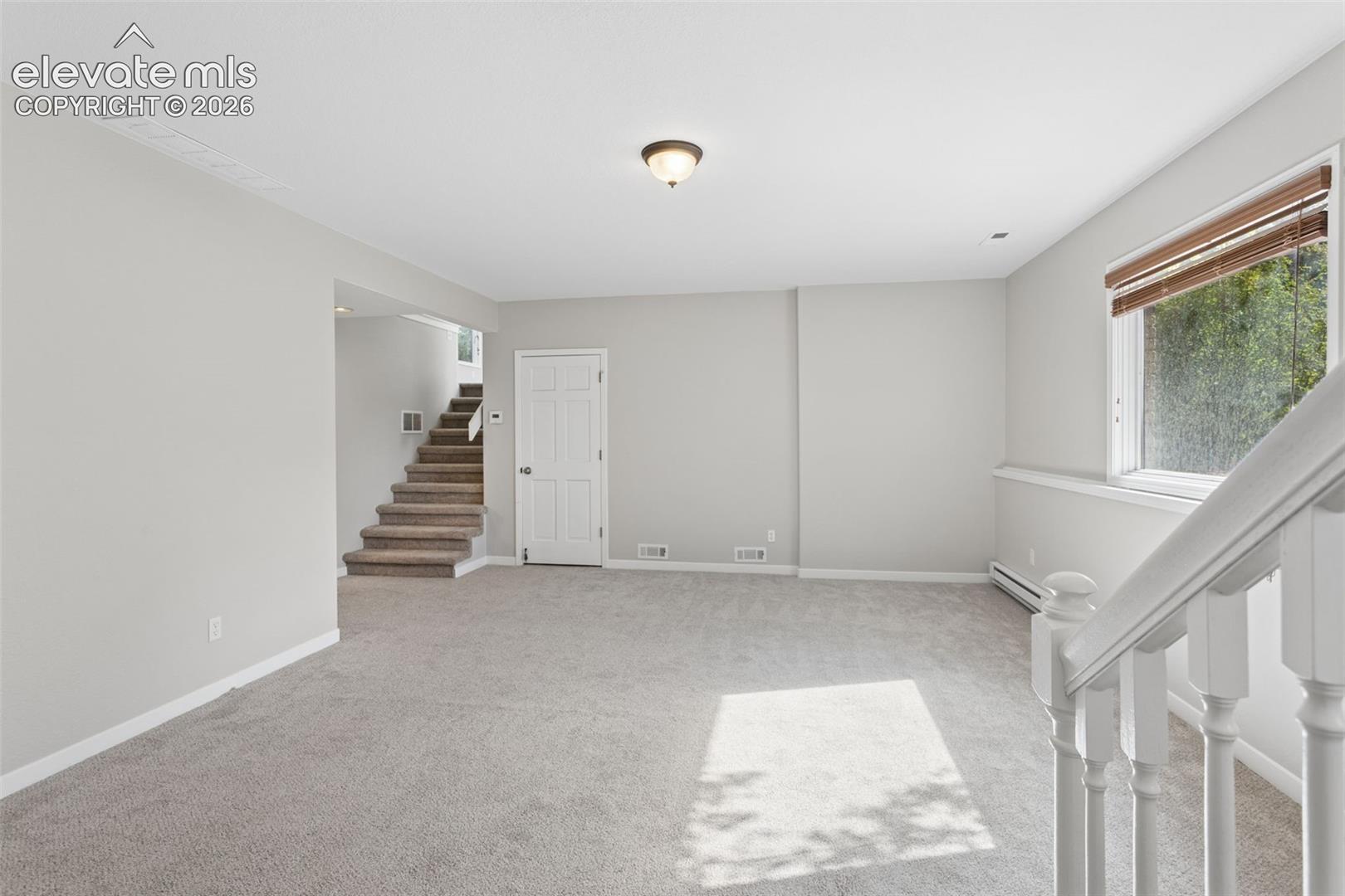 Carpeted flooring, neutral wall tones, white trim, and a window with blinds