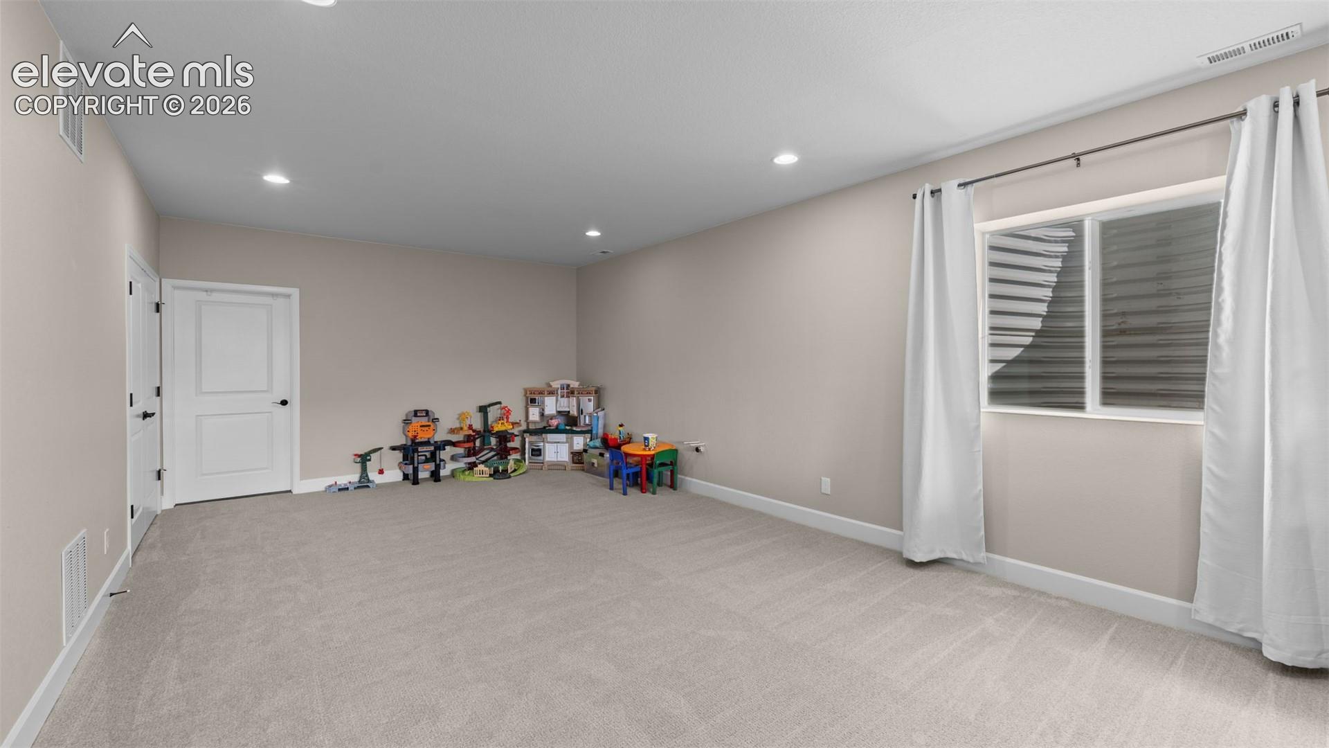 Carpeted room with recessed lighting, light-toned walls, and a window with white trim