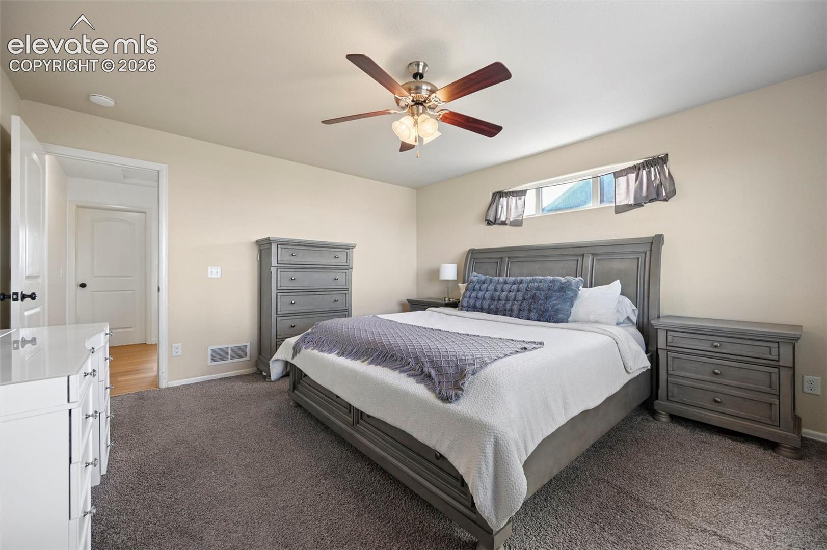 Neutral-toned interior featuring plush carpeting, multi-panel doors, and a ceiling fan with integrated lighting