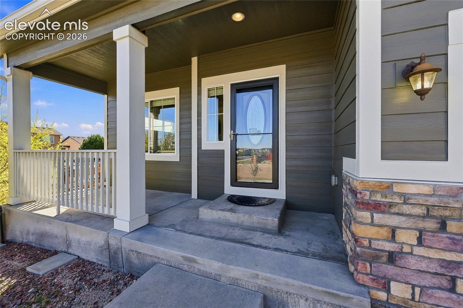 Covered front porch featuring a concrete foundation, stone-veneer siding, horizontal lap siding, and a white balustrade