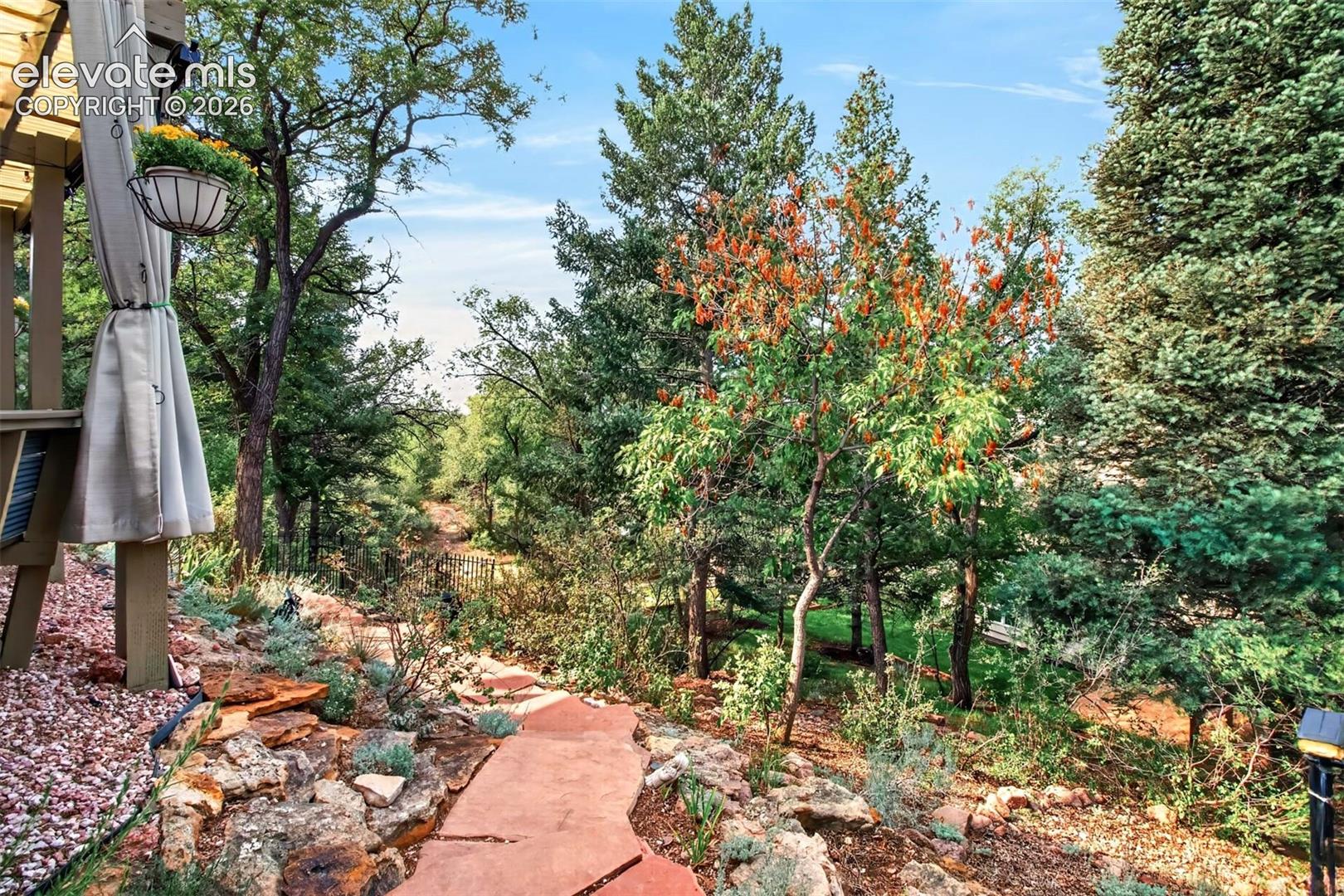Flagstone walkways meander through the lush foliage of the backyard