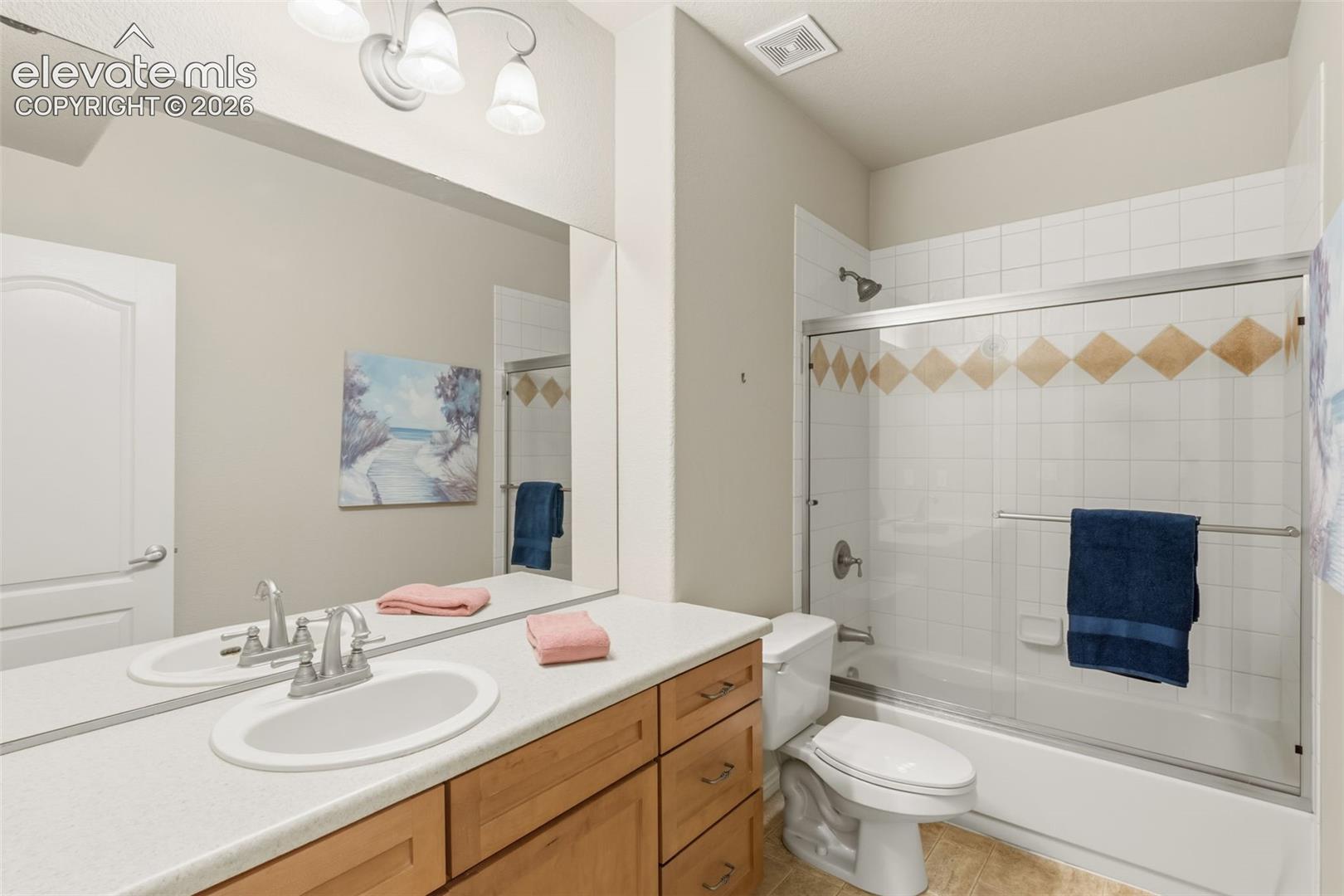 Bathroom featuring a single vanity with a laminate countertop, wood-finish cabinetry, and a full-width mirror