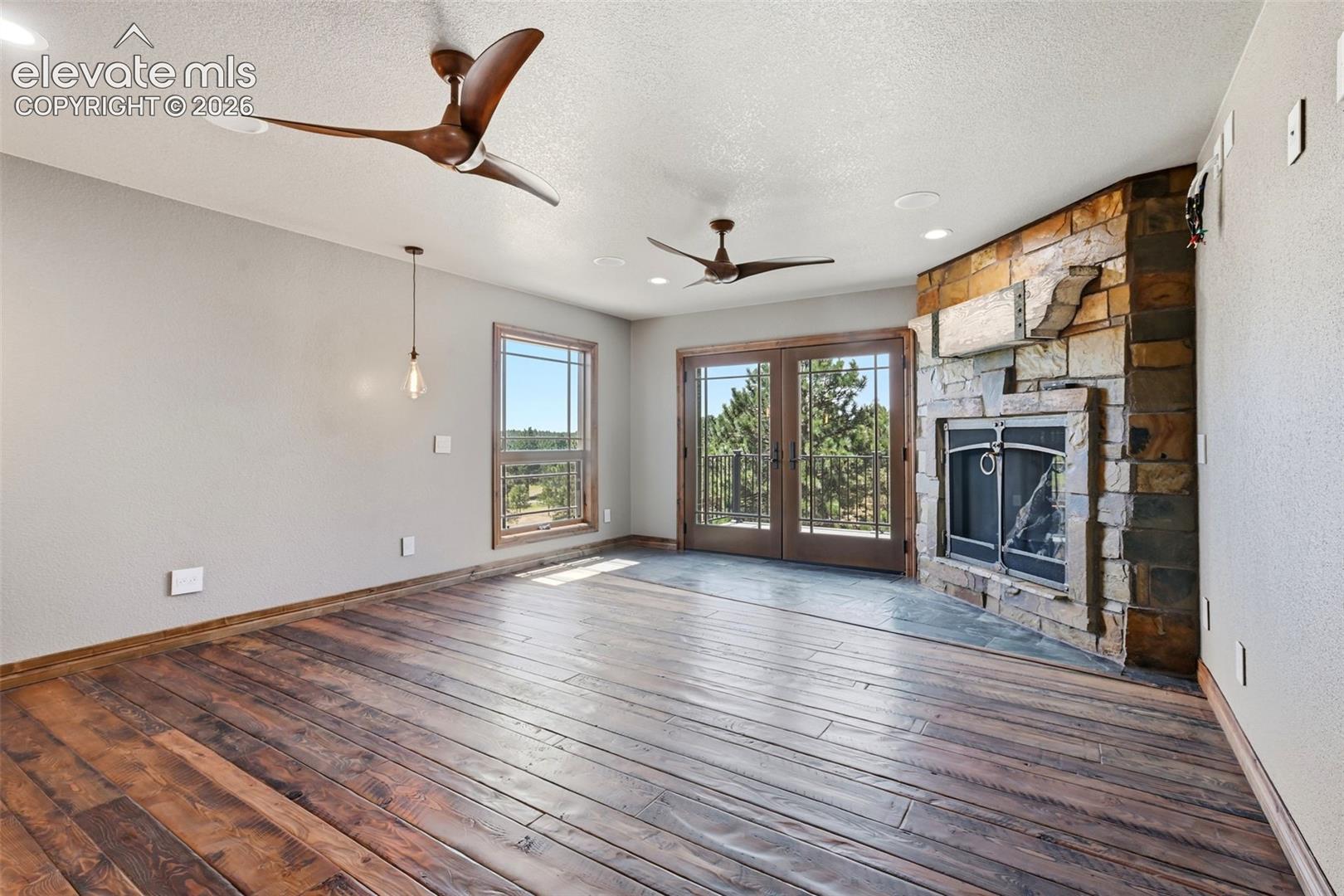 Spacious interior featuring wide-plank wood flooring and a corner fireplace with stone surround