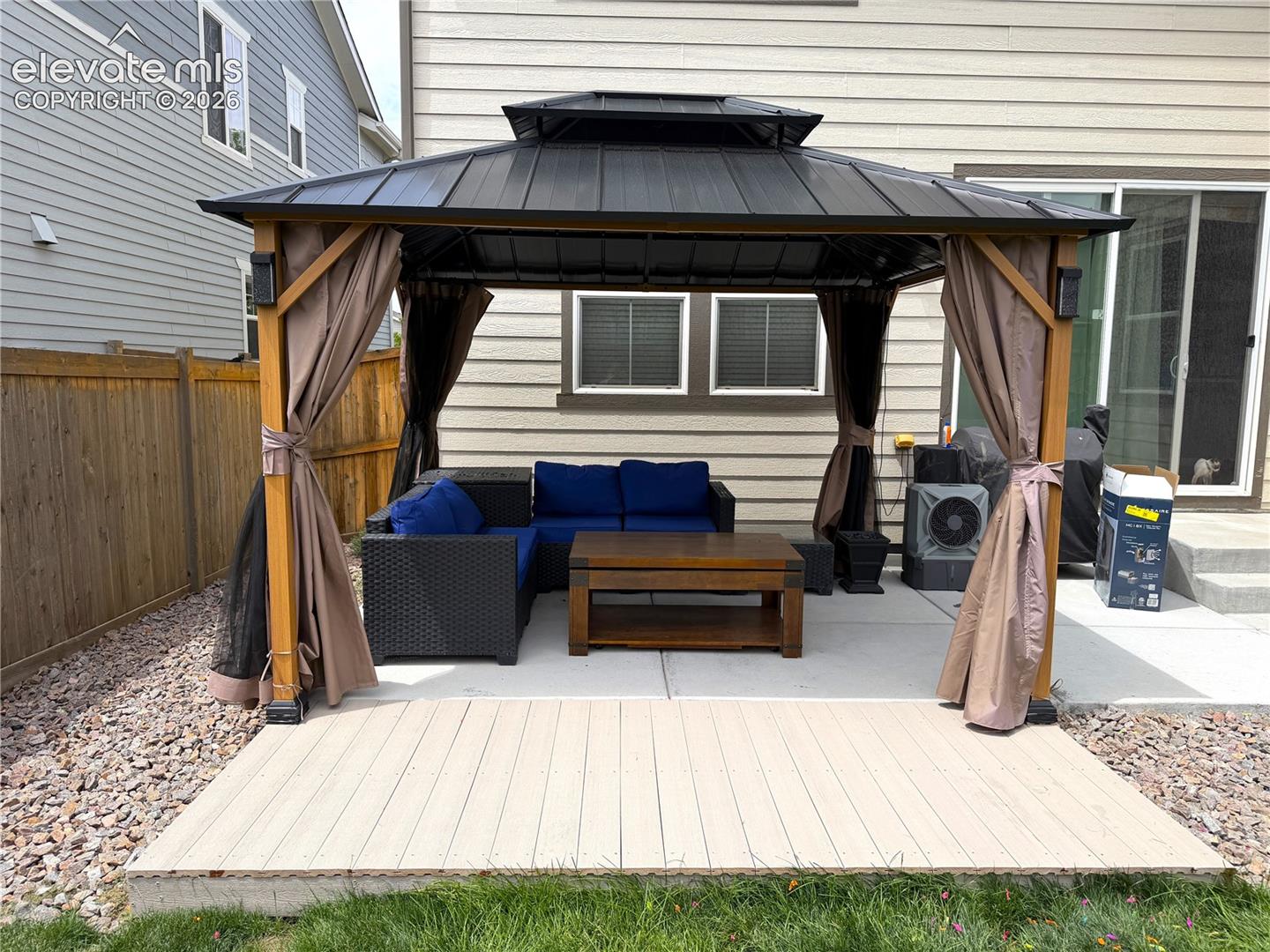 Outdoor gazebo featuring a permanent hard-top metal roof, wooden support posts, and concrete patio flooring