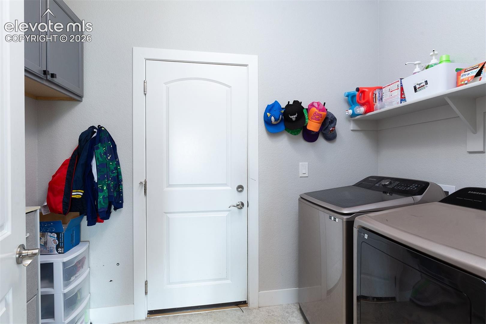 Main-level Laundry area featuring wall-mounted cabinetry, garage entry, and shelving.