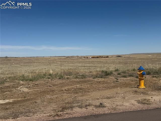The property features expansive undeveloped land with natural grasses under a clear sky