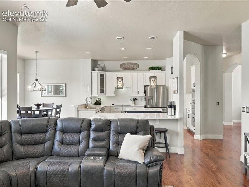 Open-concept living area with wood-finish flooring, recessed lighting, and a ceiling fan