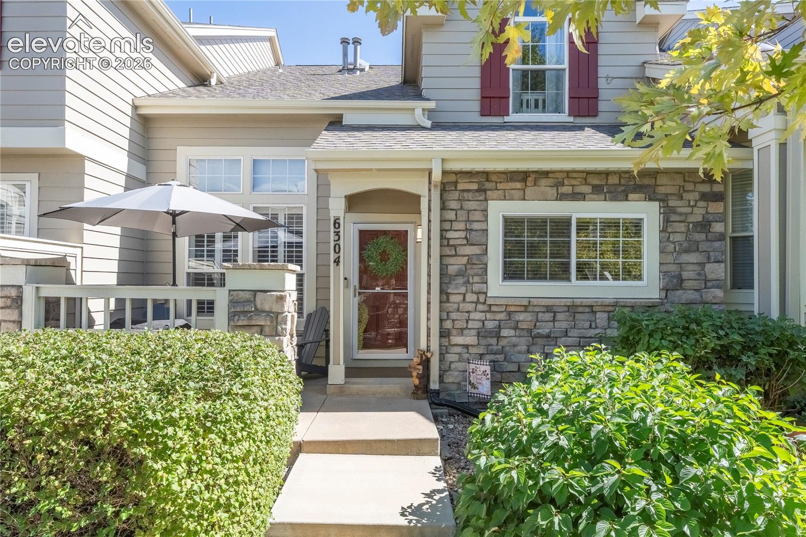 Exterior facade featuring horizontal lap siding and stone veneer masonry, a covered entryway with a concrete walkway, and shutter-accented windows