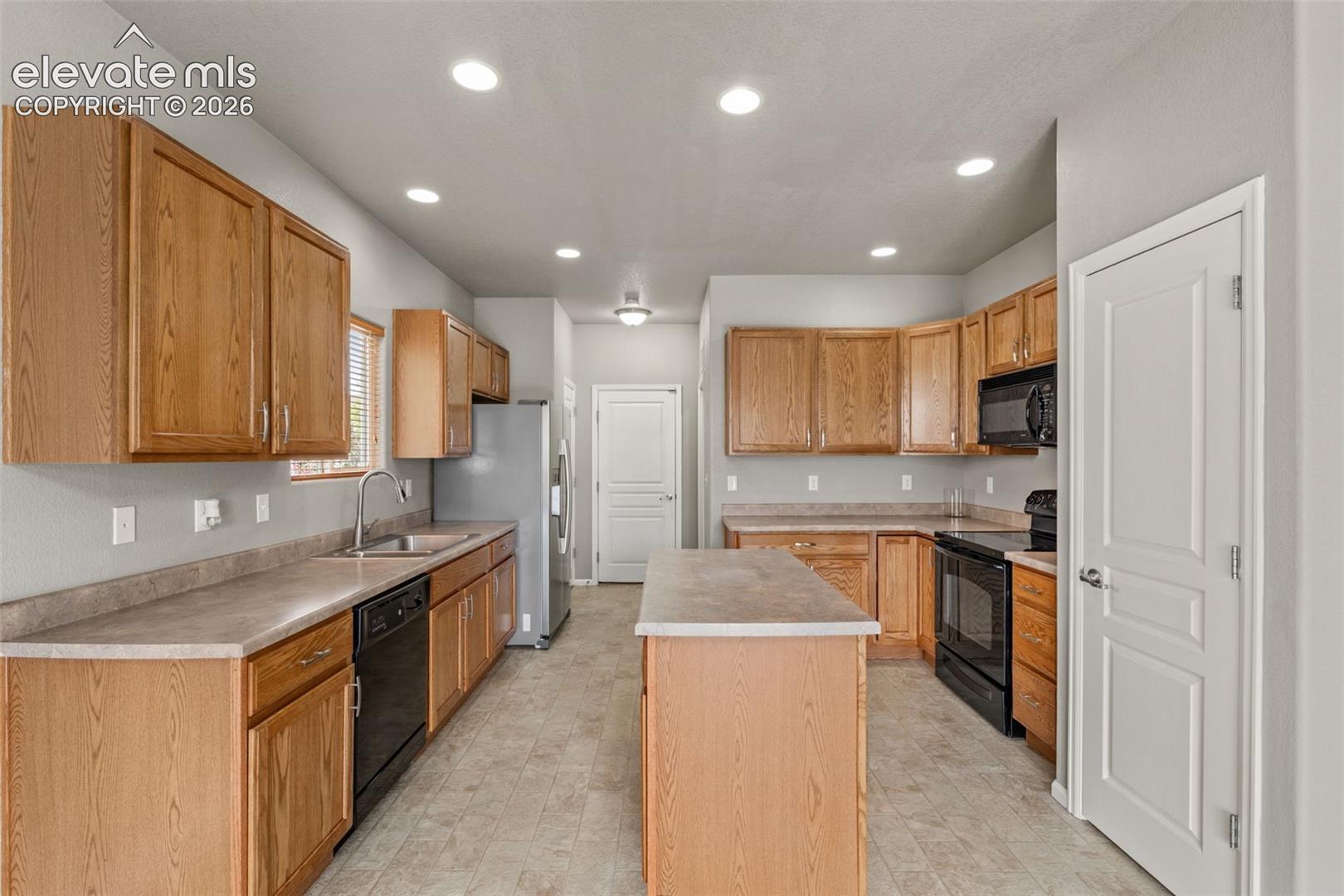 Kitchen featuring natural wood cabinetry, a center island, recessed ceiling lighting, and laminate countertops