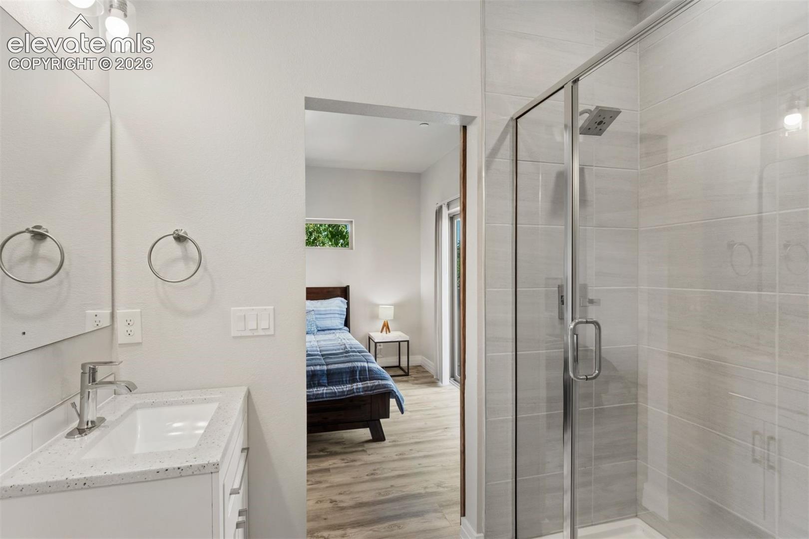 Ensuite bathroom with dual vanities, walk in shower, and walk in closet