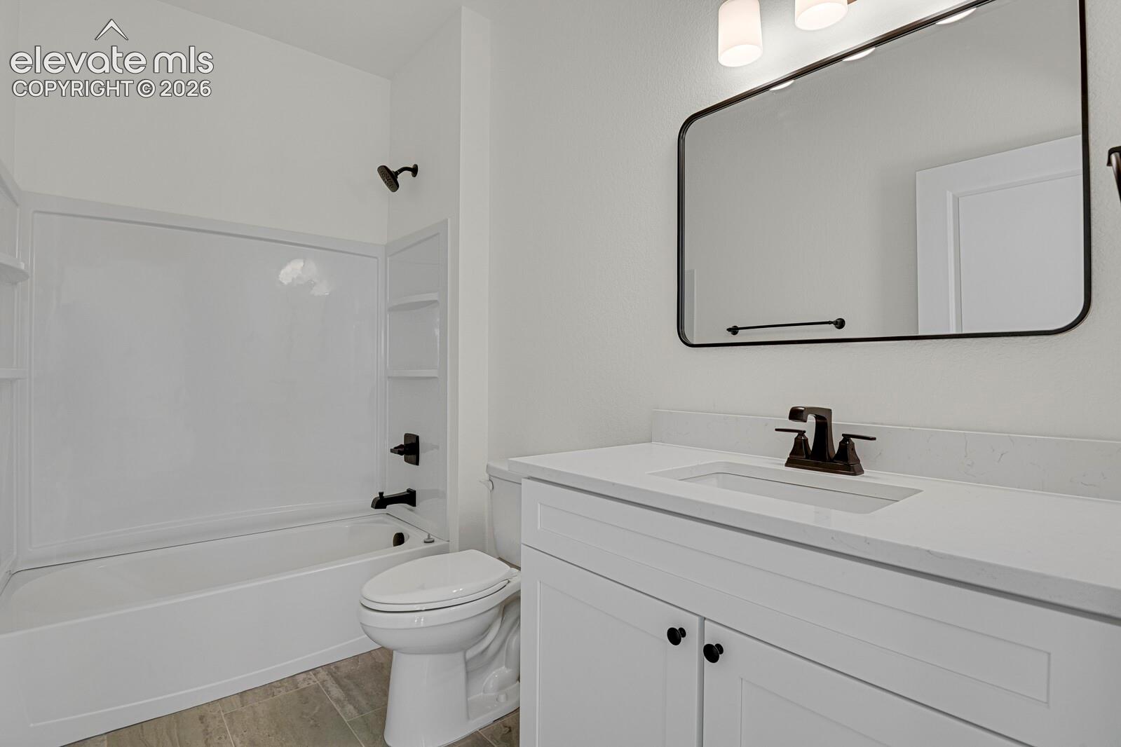 Bathroom featuring white shaker-style cabinetry, quartz countertop, rectangular undermount sink, matte black fixtures, and a framed vanity mirror