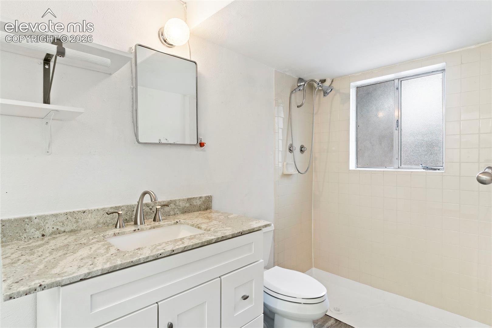 White vanity with a light-toned countertop, undermount sink, and brushed nickel faucet