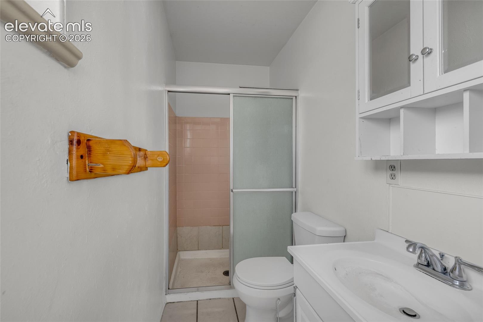 White vanity with integrated sink, chrome faucet, and white cabinetry with glass-front uppers