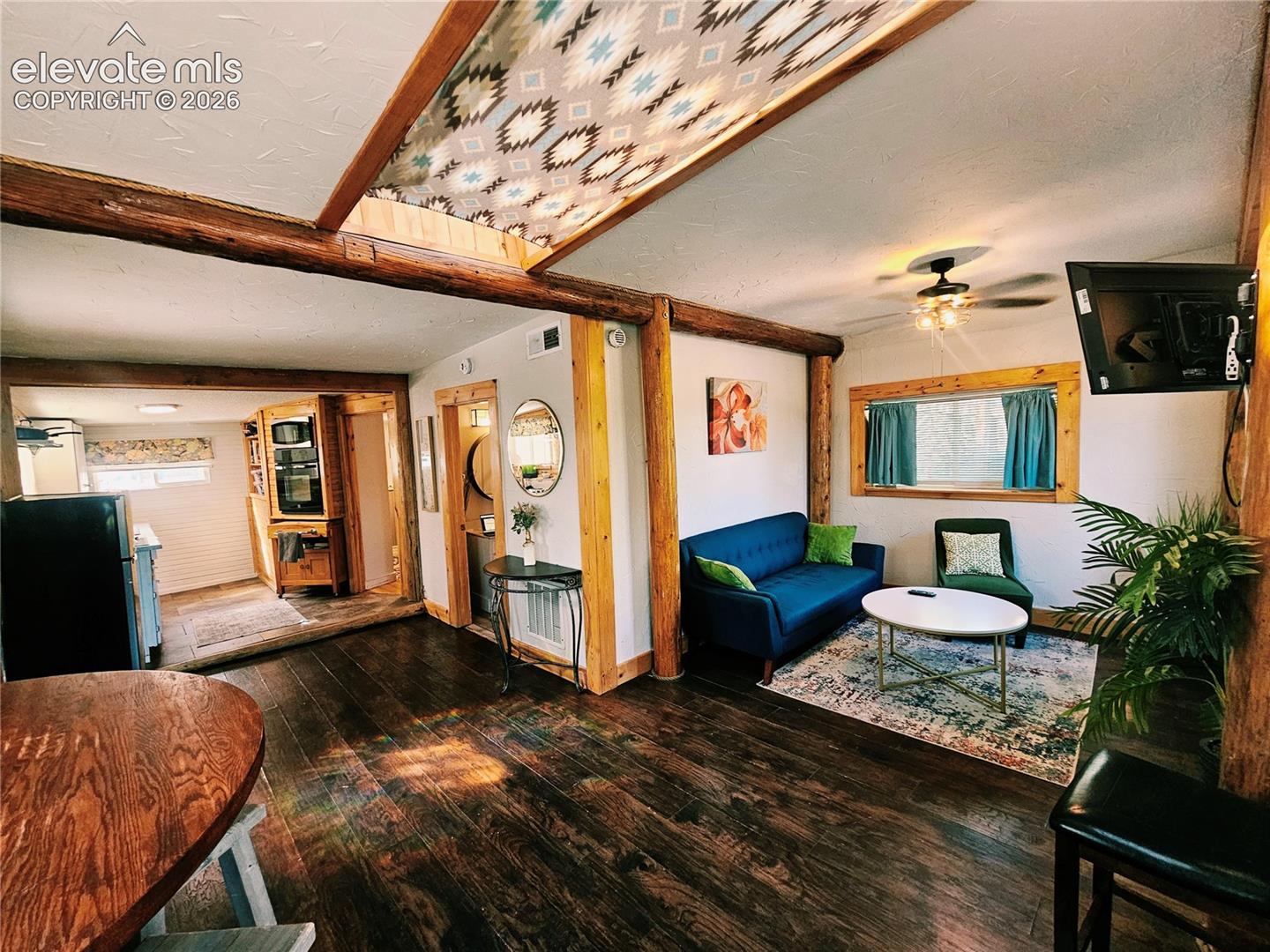 Exposed wood beams, recessed lighting, ceiling fan light fixture, and a kitchen entry