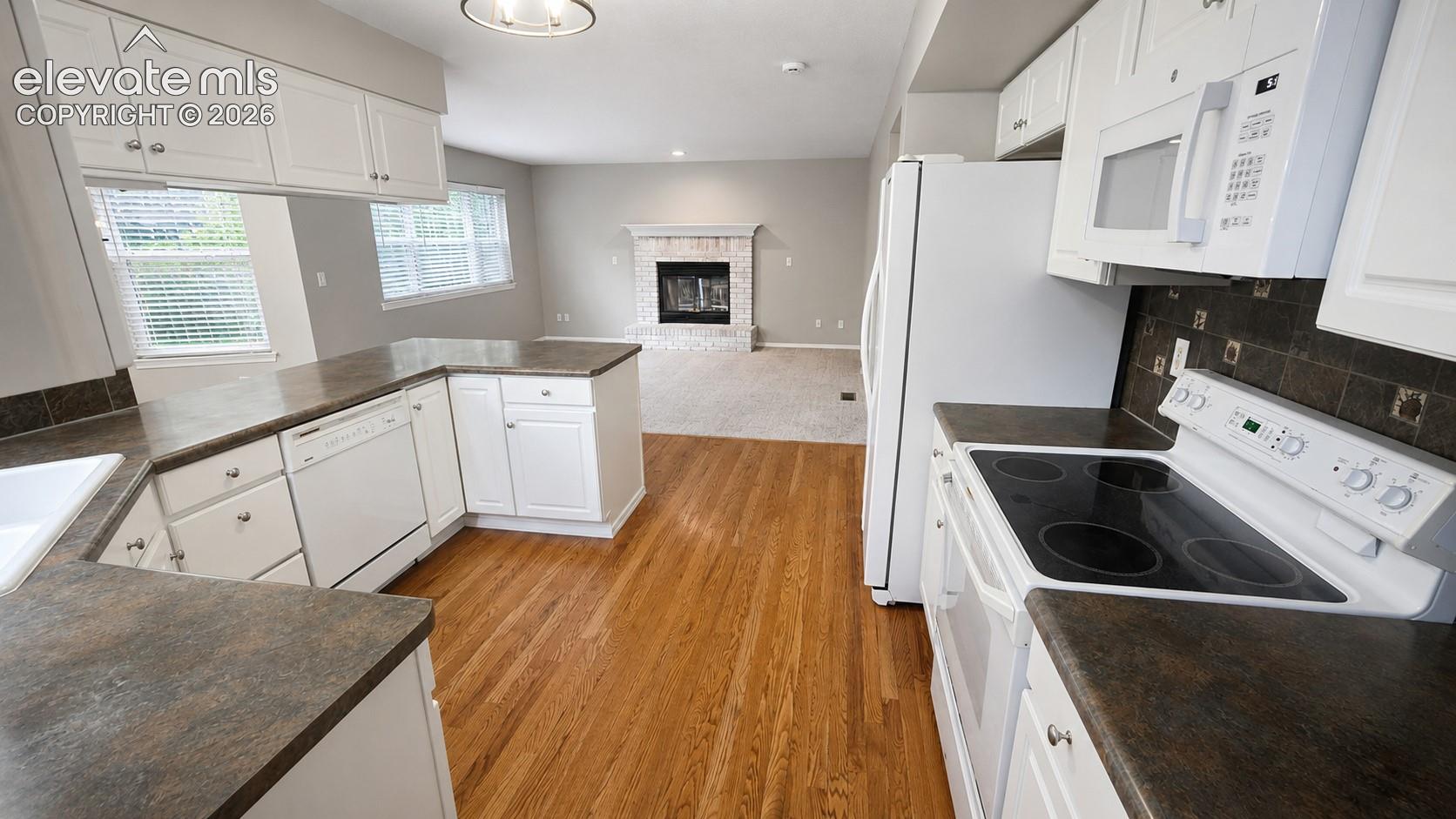 Kitchen featuring white cabinetry, dark countertops, built-in dishwasher, and electric range