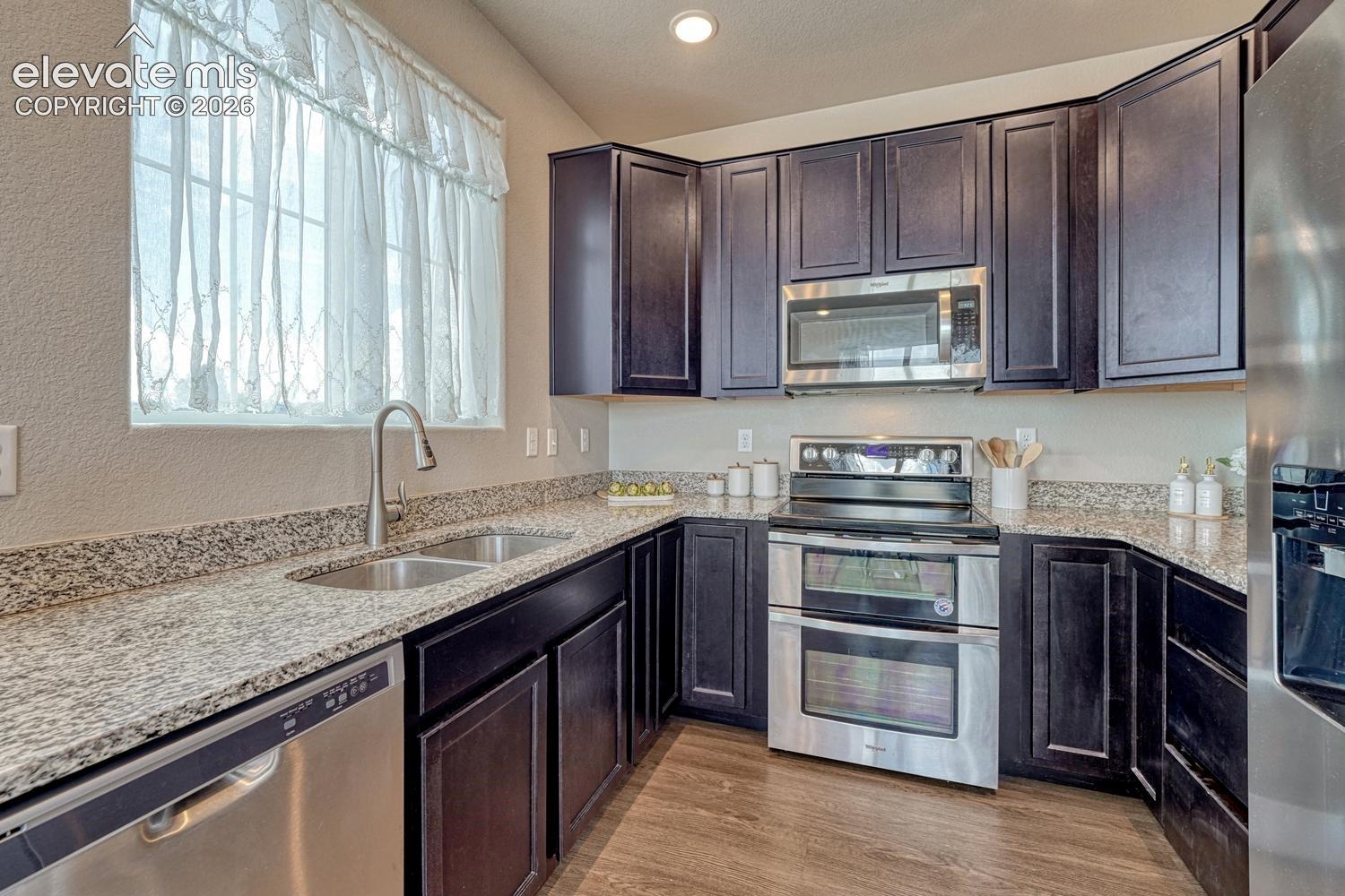 The Kitchen features dark wood cabinetry, granite countertops, and stainless steel appliances.