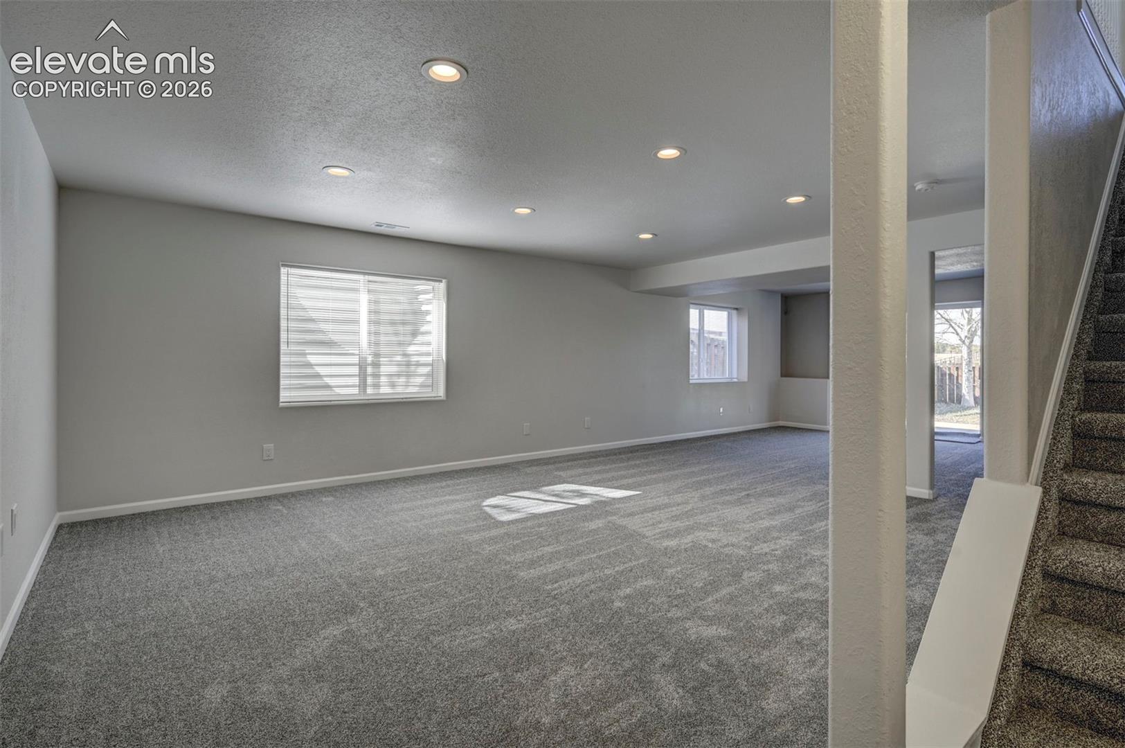 Neutral interior space featuring wall-to-wall carpeting, recessed ceiling lighting, and windows with integrated blinds