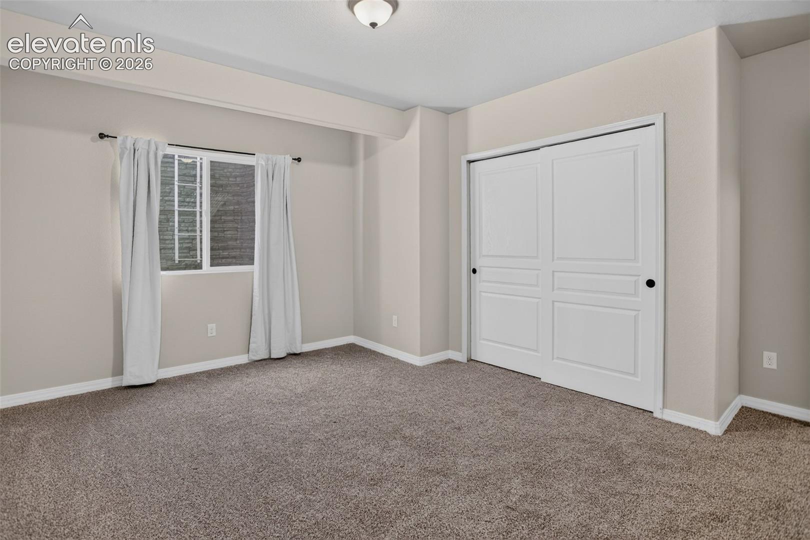Recessed lighting, neutral wall paint, textured carpet flooring, and a window with white trim
