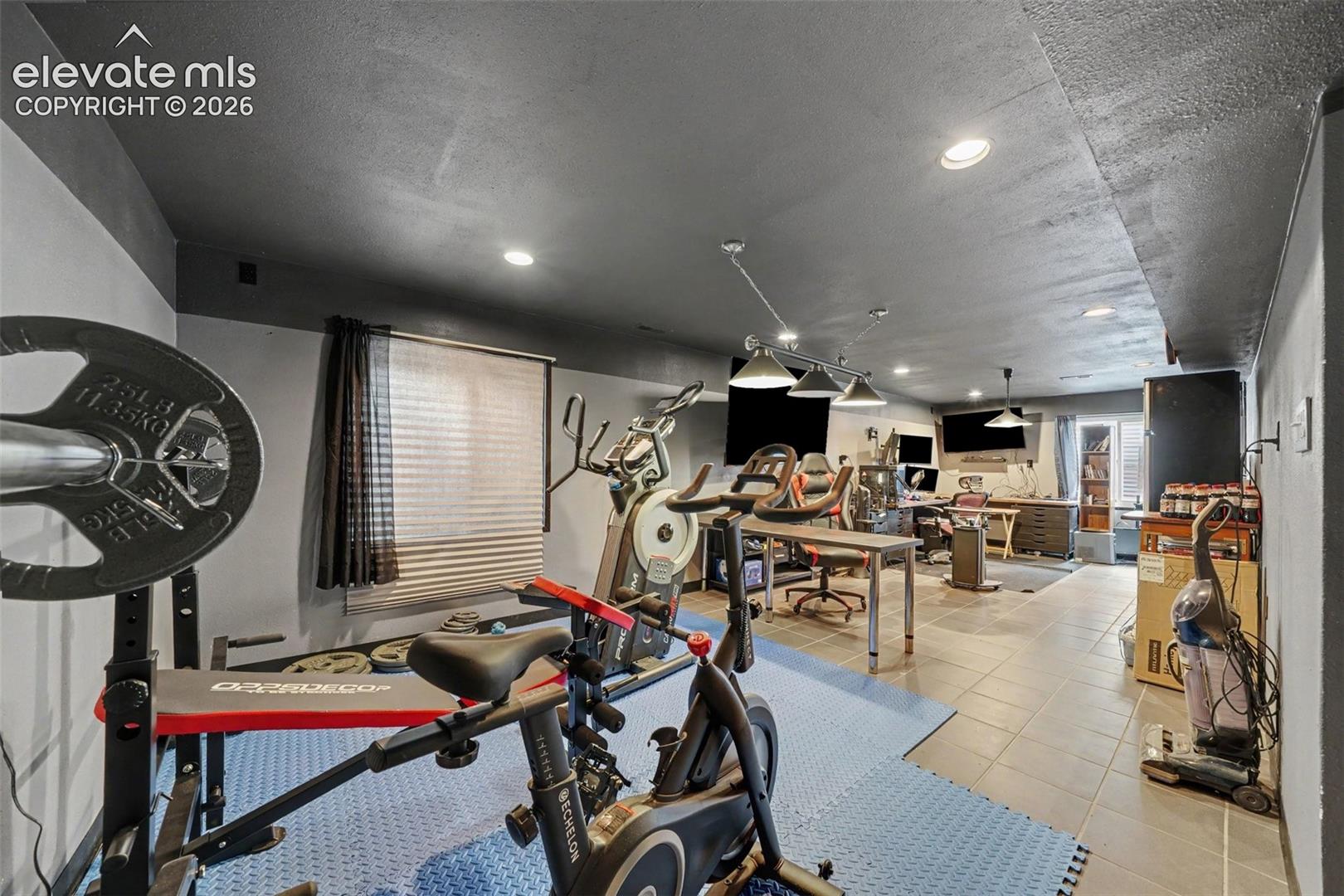 Large room featuring tile flooring, recessed ceiling lighting, multi-pendant track lighting, and dual-tone painted walls