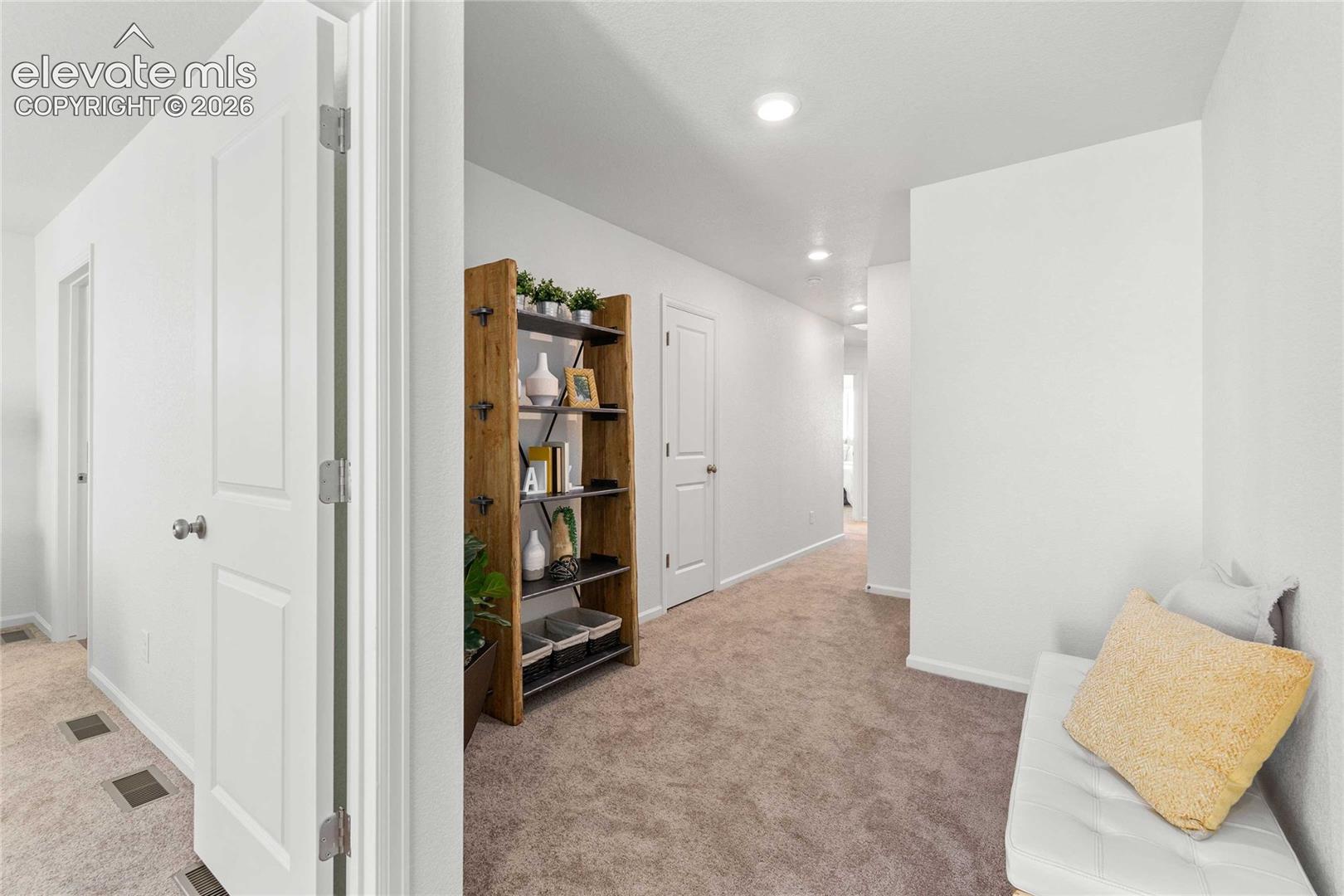 Recessed lighting illuminates the carpeted hallway with white walls and trim
*photos  of a model home*