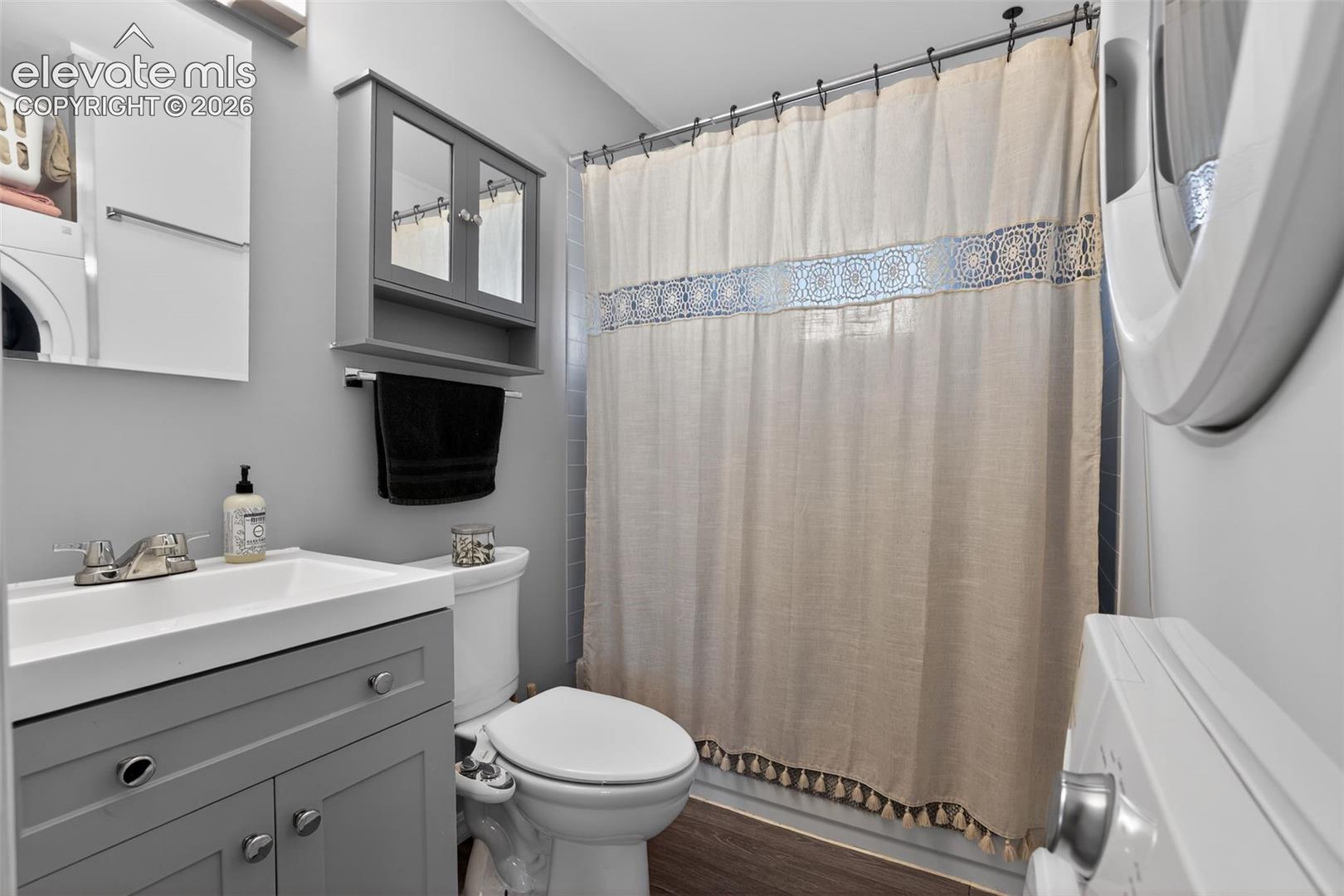 Bathroom featuring a vanity with a rectangular sink, wall-mounted mirrored medicine cabinet, built-in shelving, and wood-finish flooring