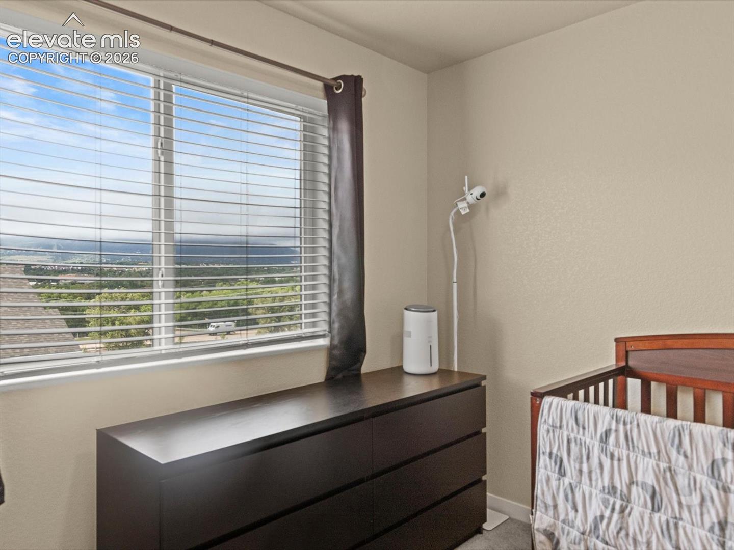 Expansive window featuring horizontal blinds and a distant landscape