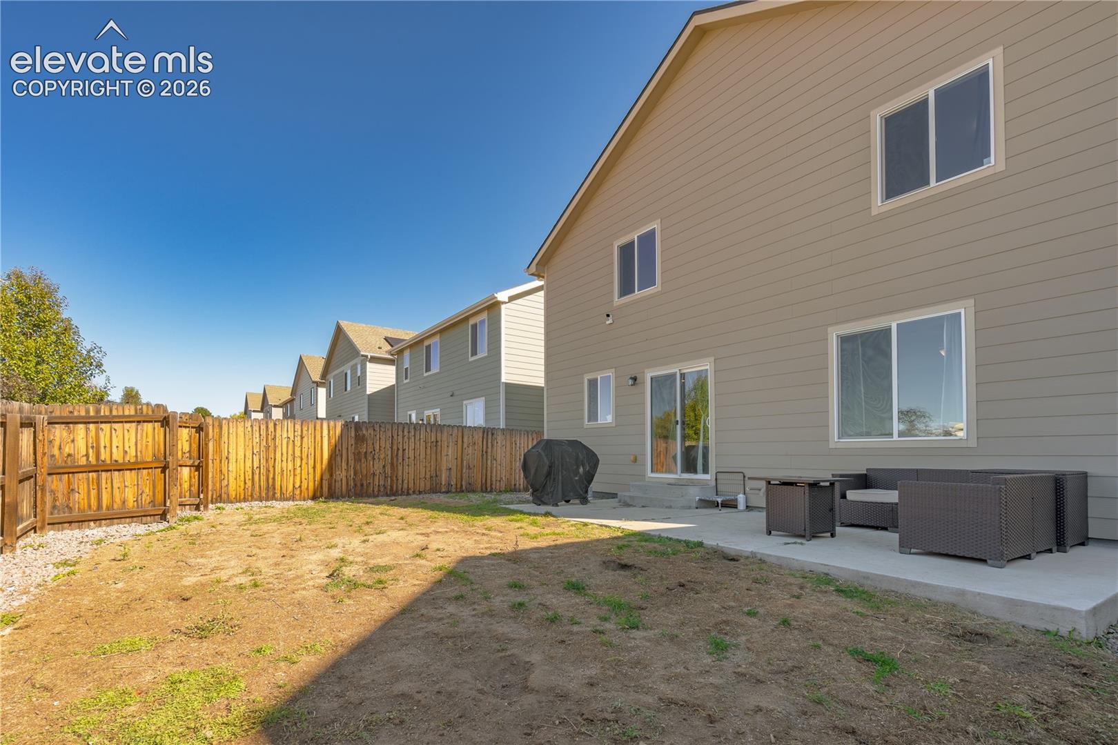 Rear exterior featuring horizontal lap siding, a concrete patio, and a wood privacy fence