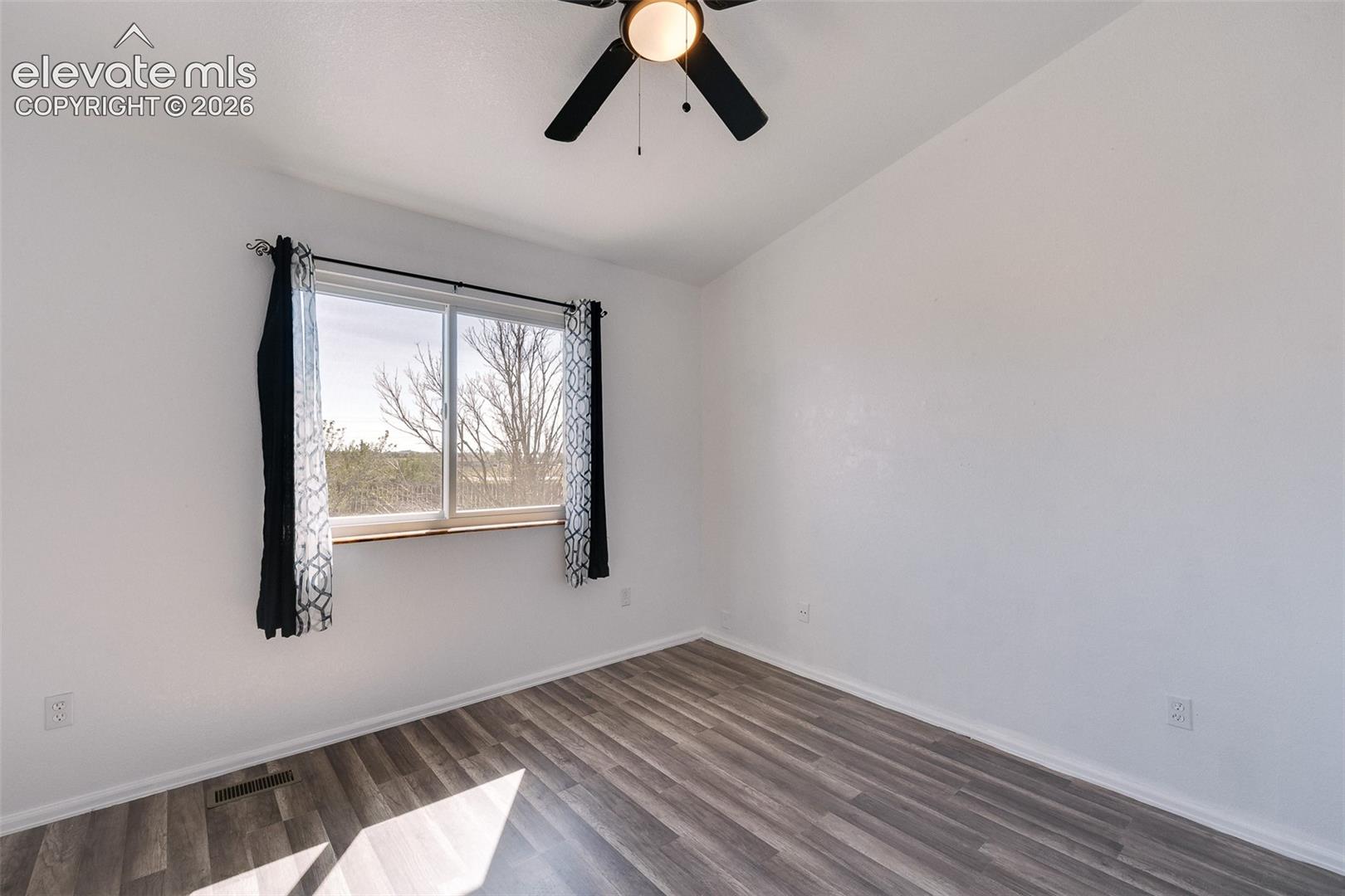 Vaulted Main Level Bedroom #2 has a lighted ceiling fan and luxury vinyl plank flooring.