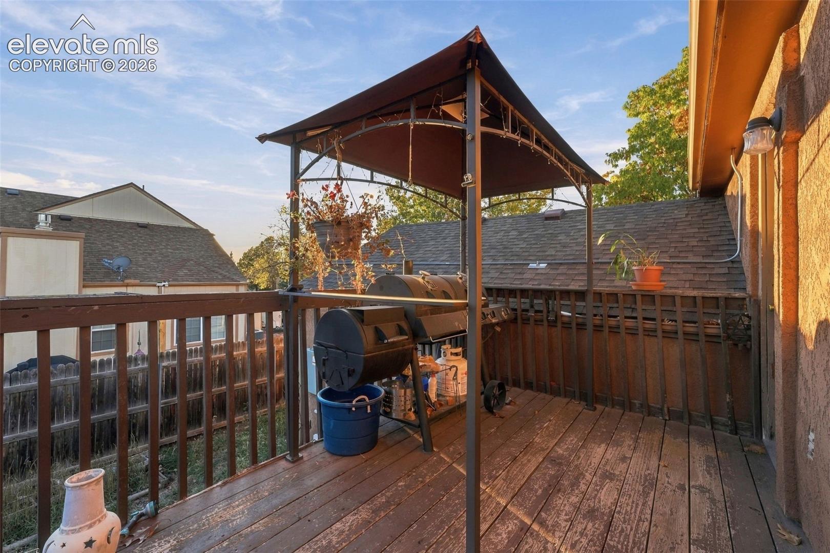Elevated wooden deck featuring metal railings and a metal-frame canopy