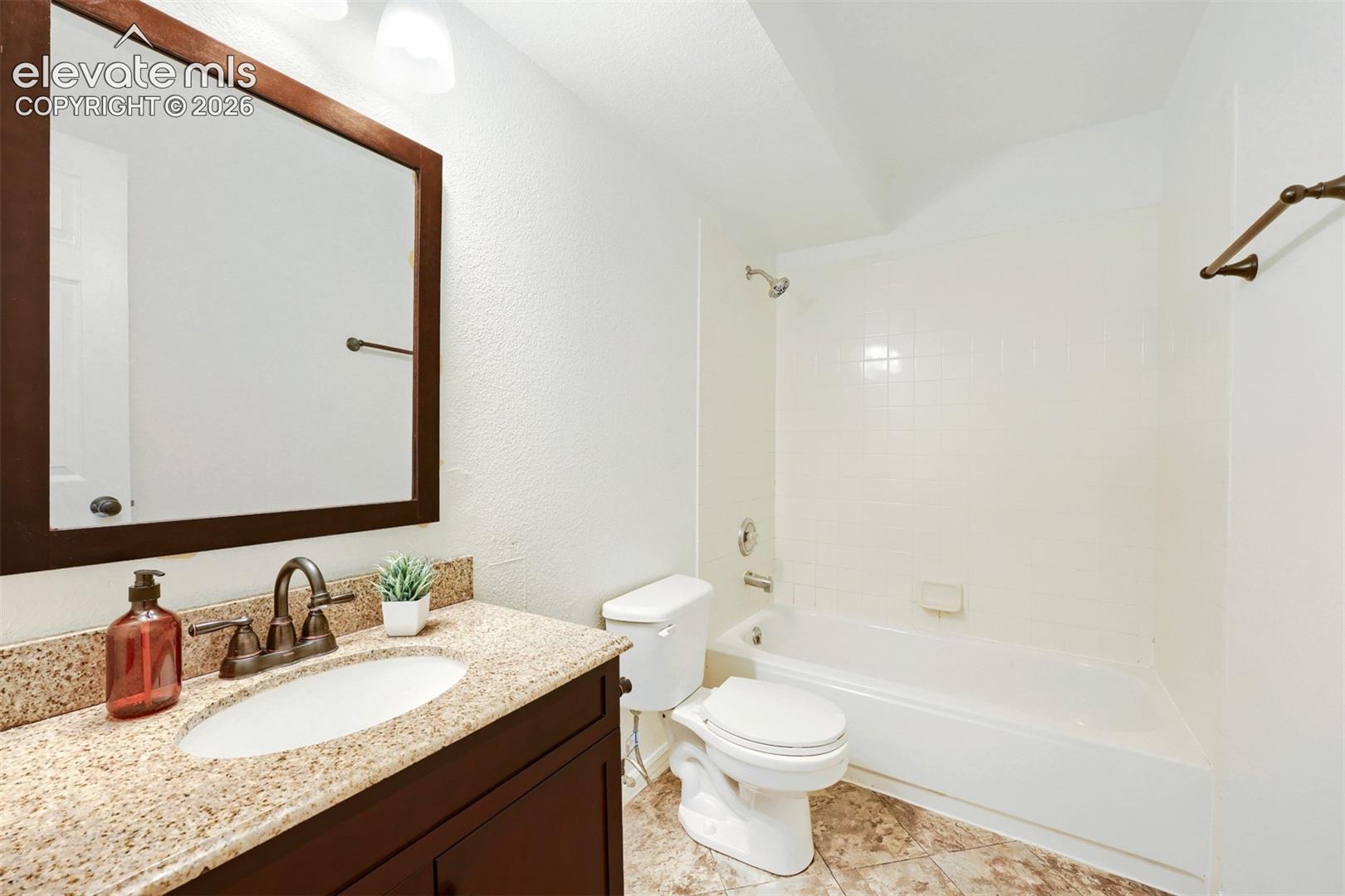 Vanity with integrated sink, stone-finish countertop, and dark-finish cabinetry