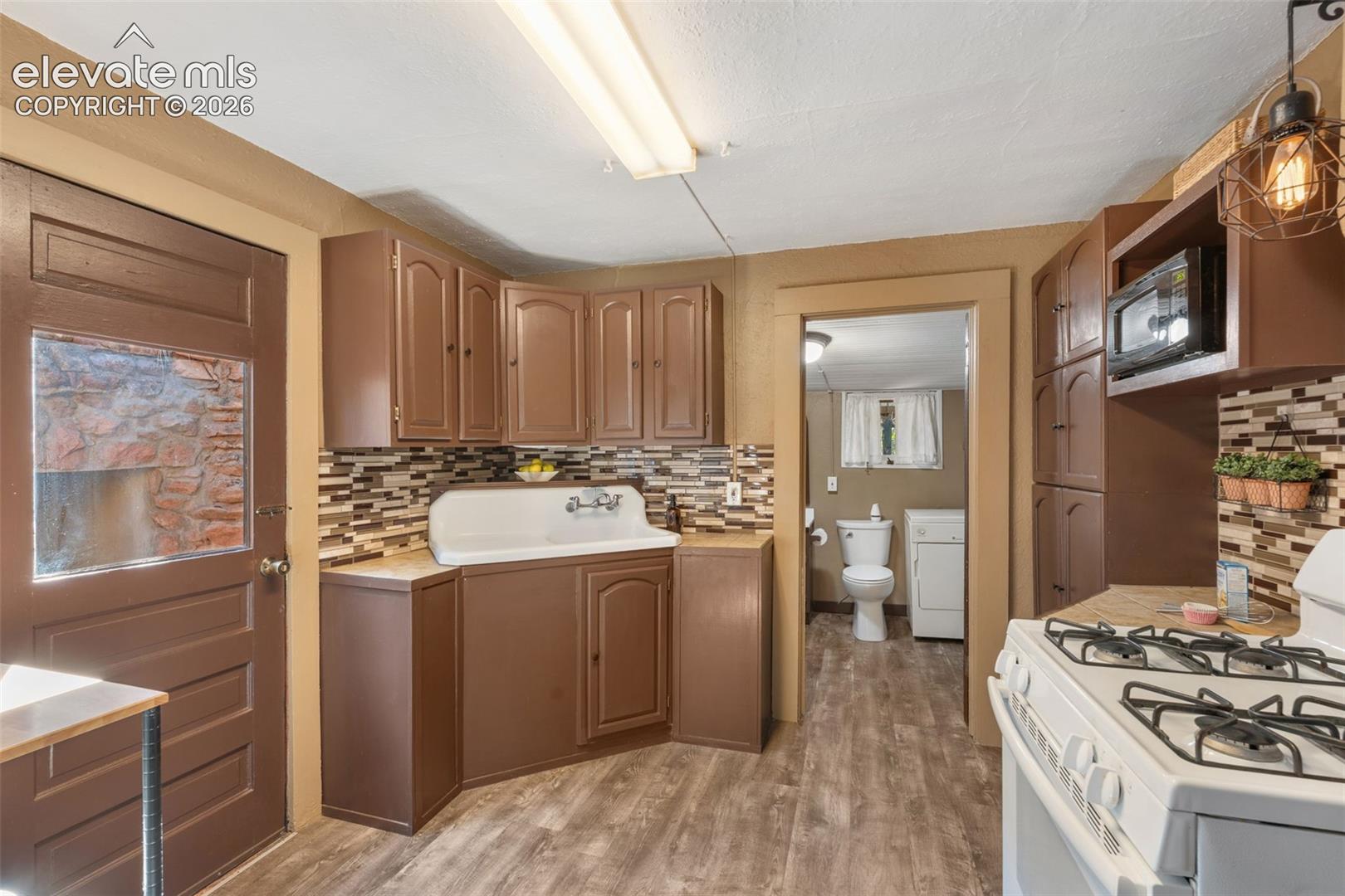 Kitchen featuring wood-finish flooring, brown cabinetry, and a mosaic tile backsplash