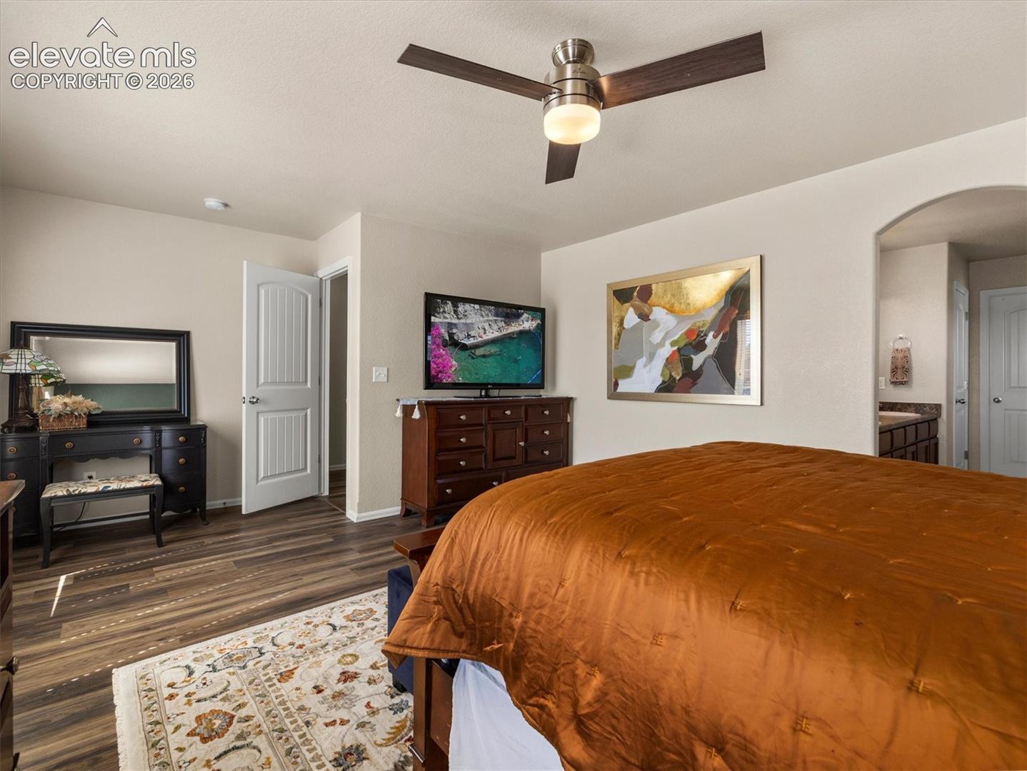 LVP flooring, ceiling fan with integrated lighting, arched doorway, and white paneled interior doors