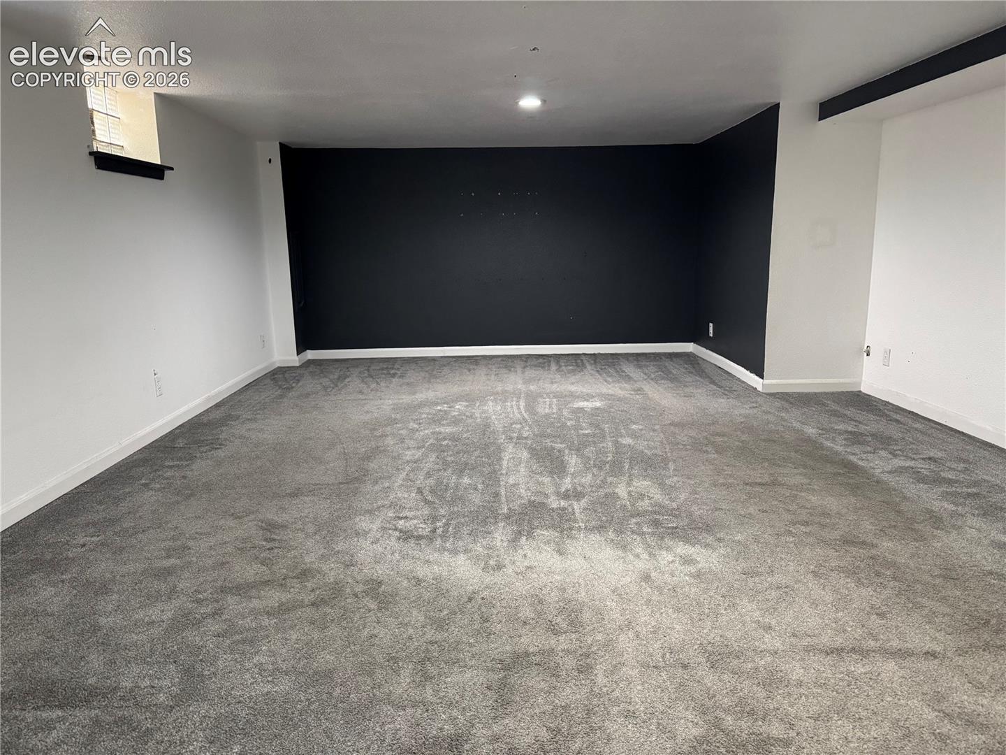 Neutral-toned carpeting, recessed ceiling lighting, and a high-contrast black accent wall