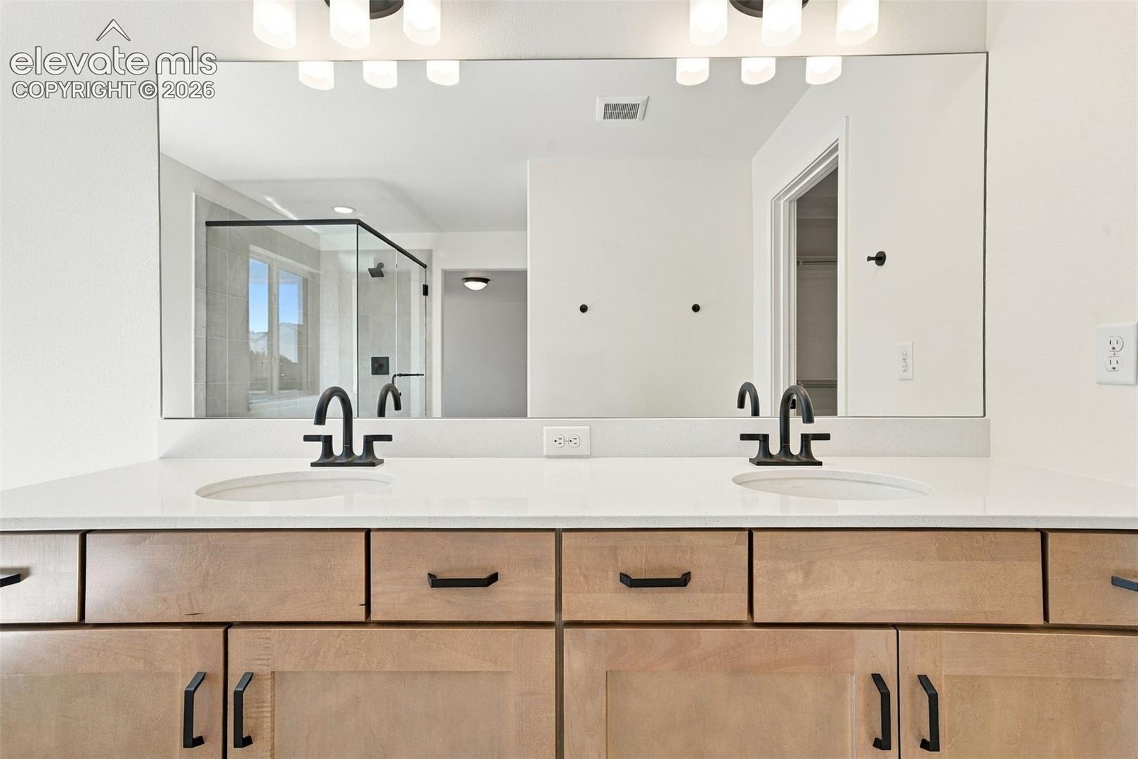 Double Vanities with undermount sinks, maple cabinets with pecan stain, matte black hardware, and quartz countertop.