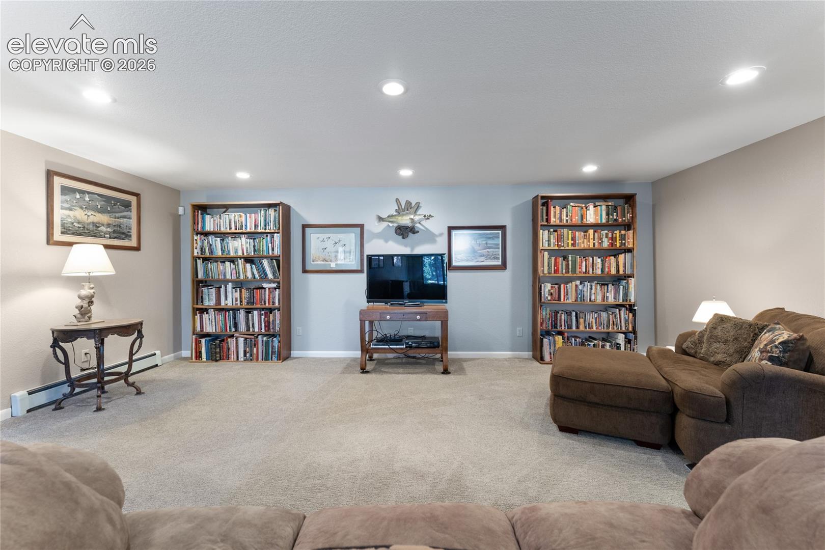 Carpeted interior space featuring recessed lighting and built-in bookshelves