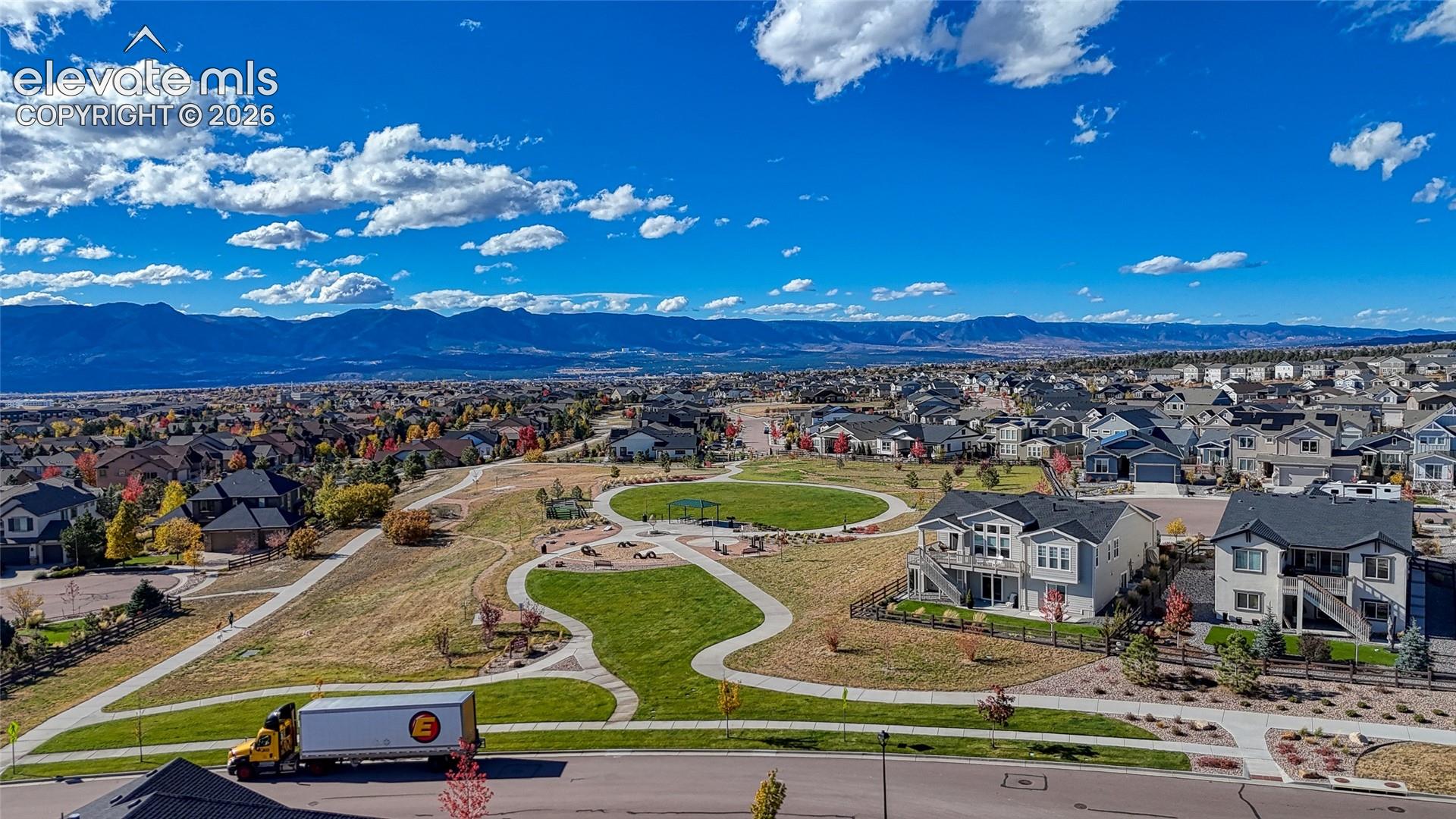 Aerial perspective featuring expansive open space, paved walking paths, a central recreational area, and mountain backdrops