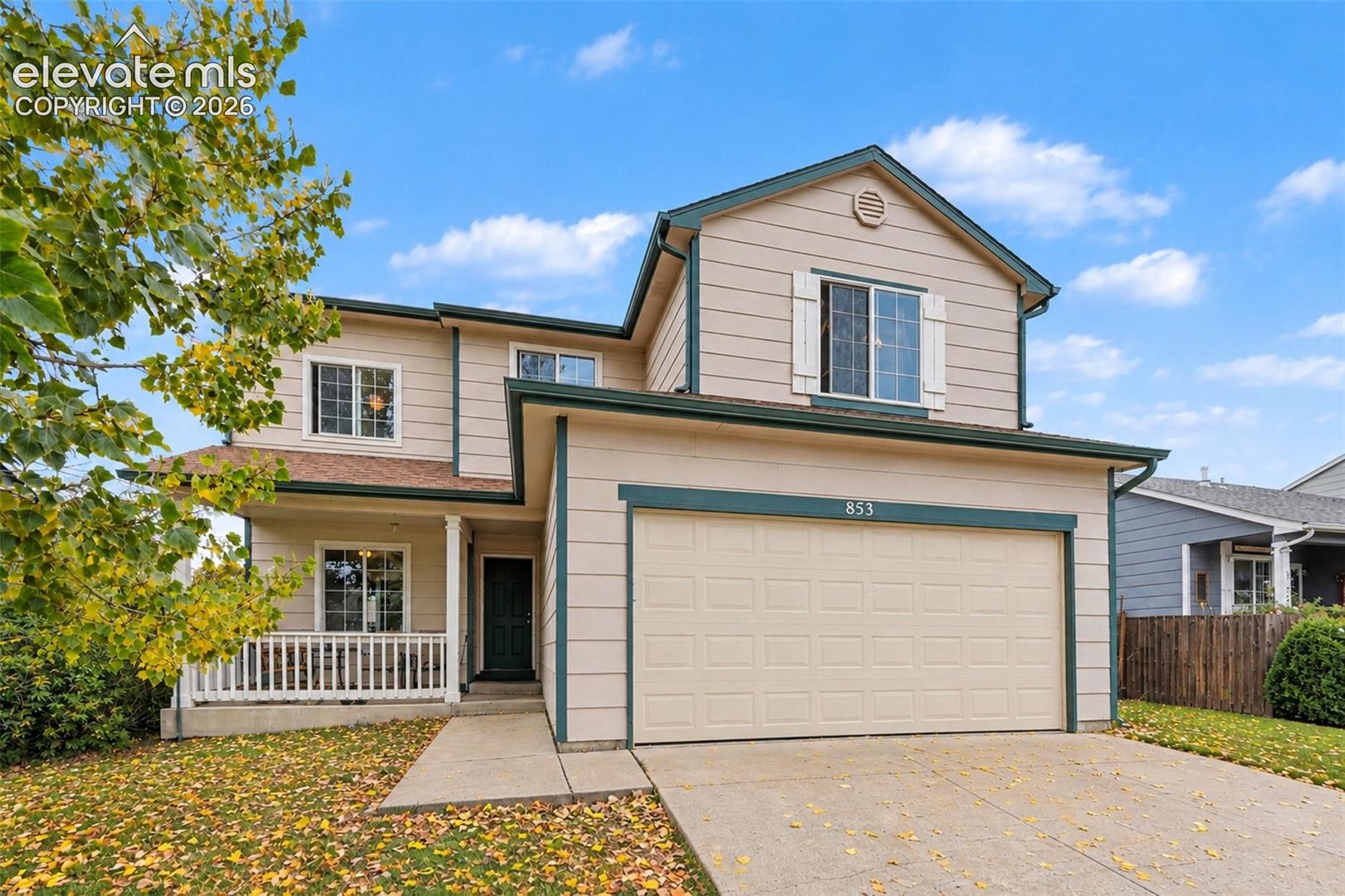 Two-story residence featuring horizontal siding, a covered front porch with white railing, a double-width concrete driveway, and attached two-car garage