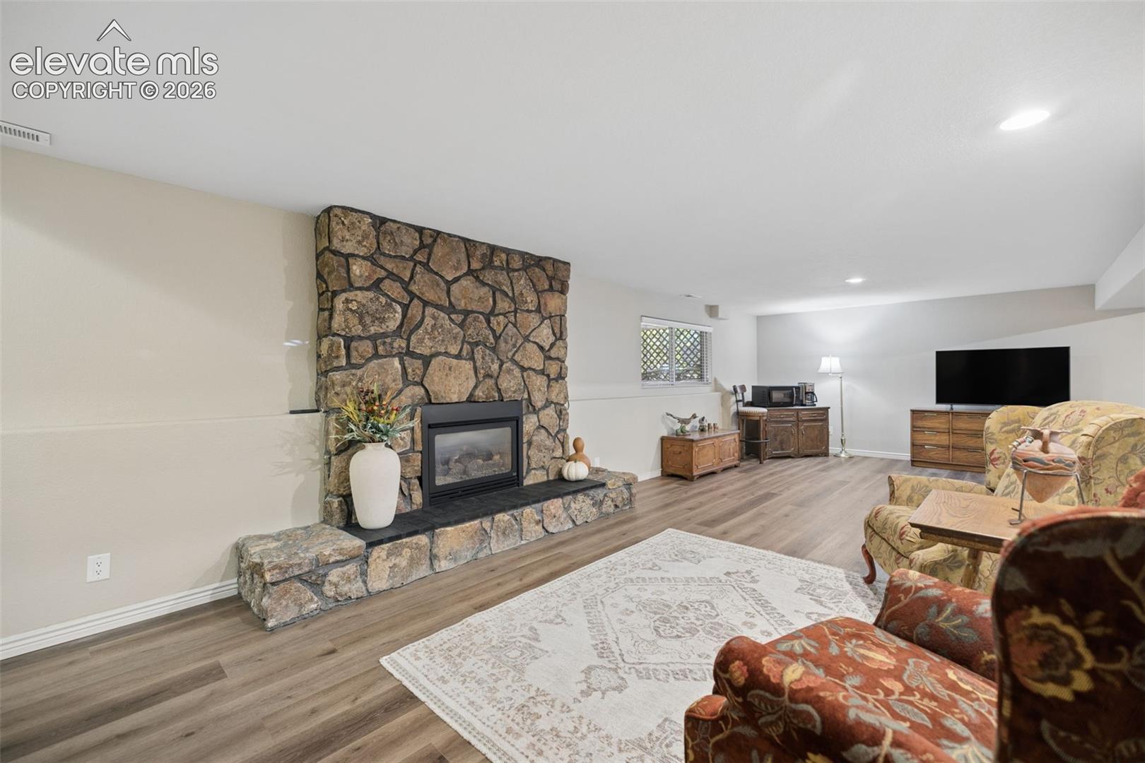 Spacious basement flex room with gas fireplace with stone surround and LVP flooring