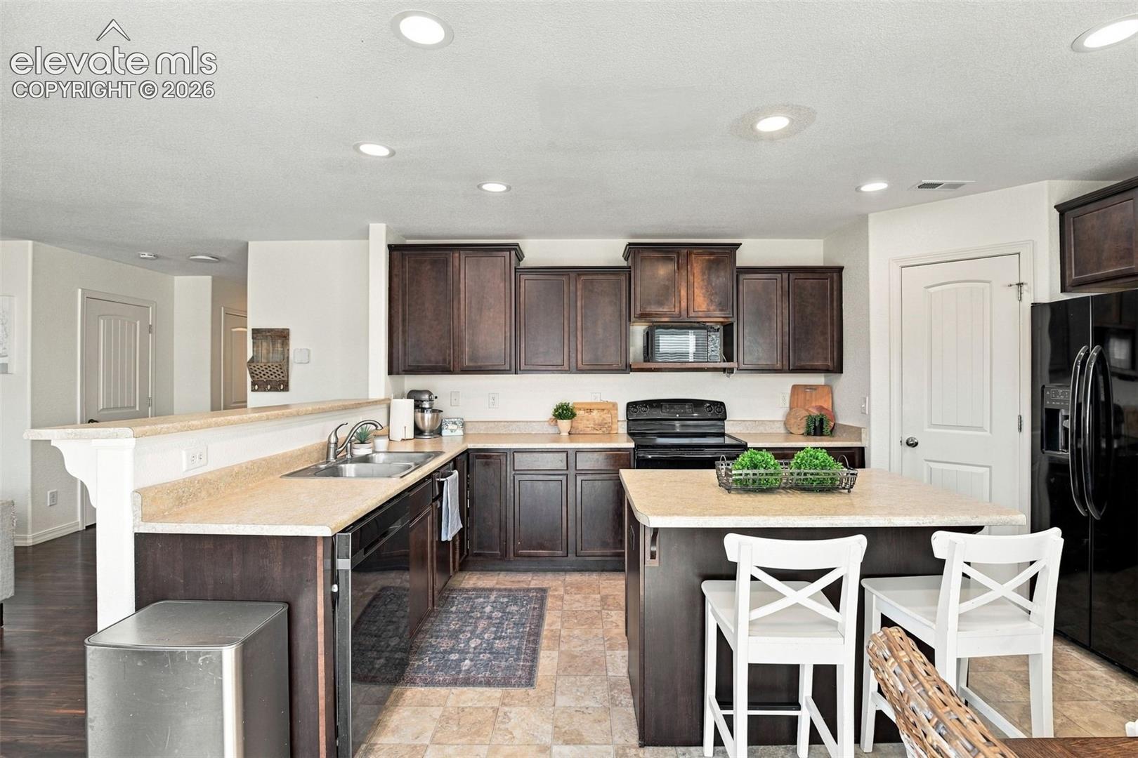 Kitchen featuring dark wood-finish cabinetry, light-toned countertops, and recessed lighting