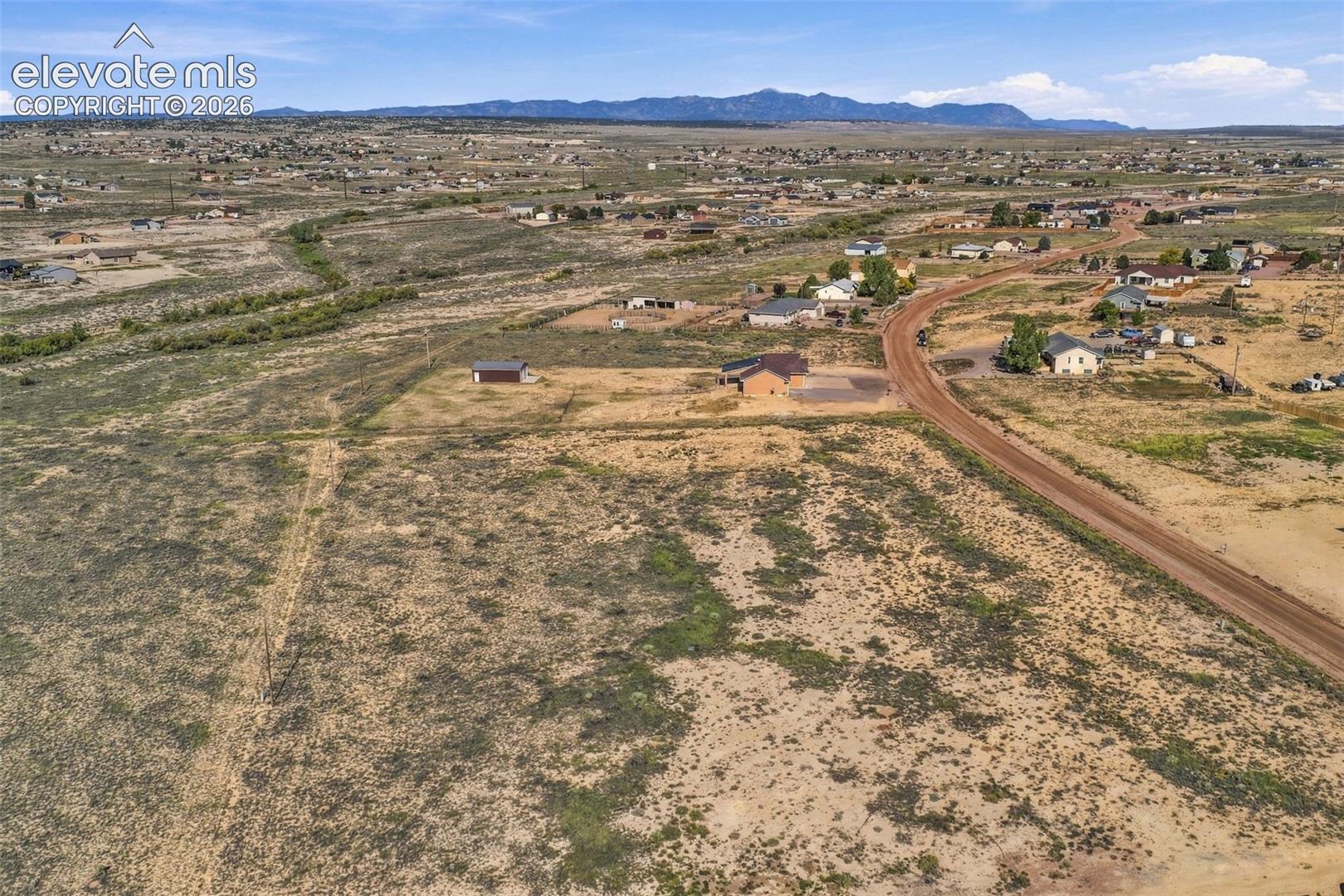 Expansive acreage featuring native landscape, a dirt road frontage, and a mountain range backdrop