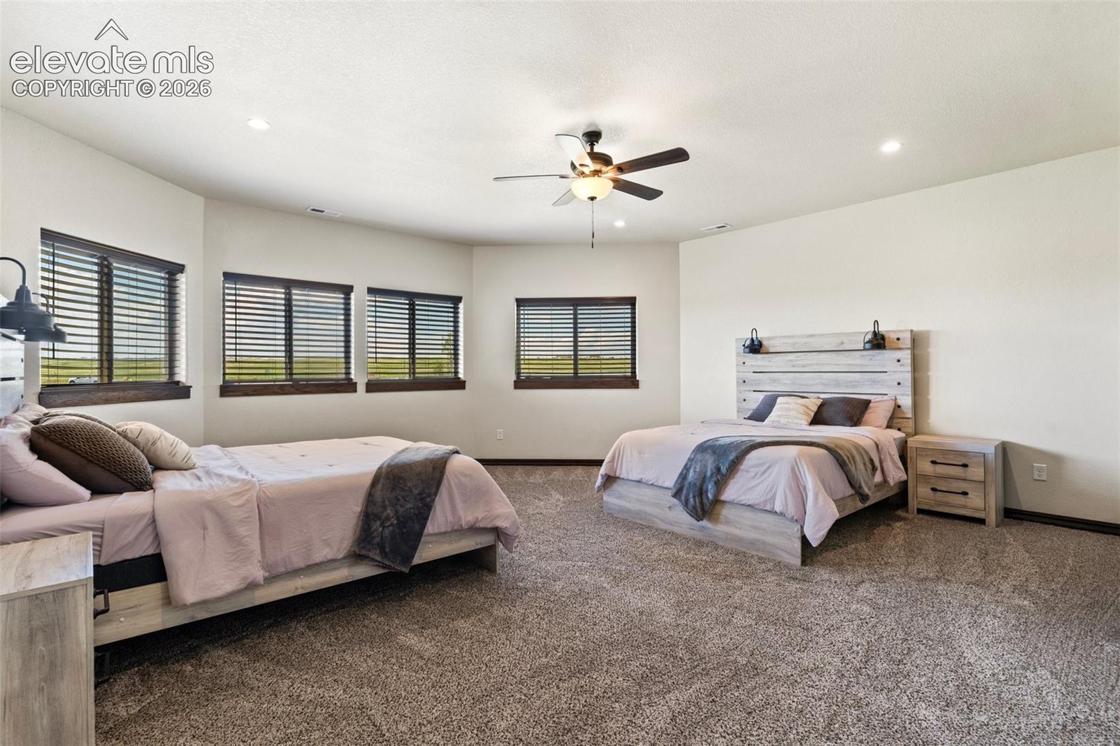 Spacious room featuring multiple windows with dark wood trim, recessed lighting, and a ceiling fan
