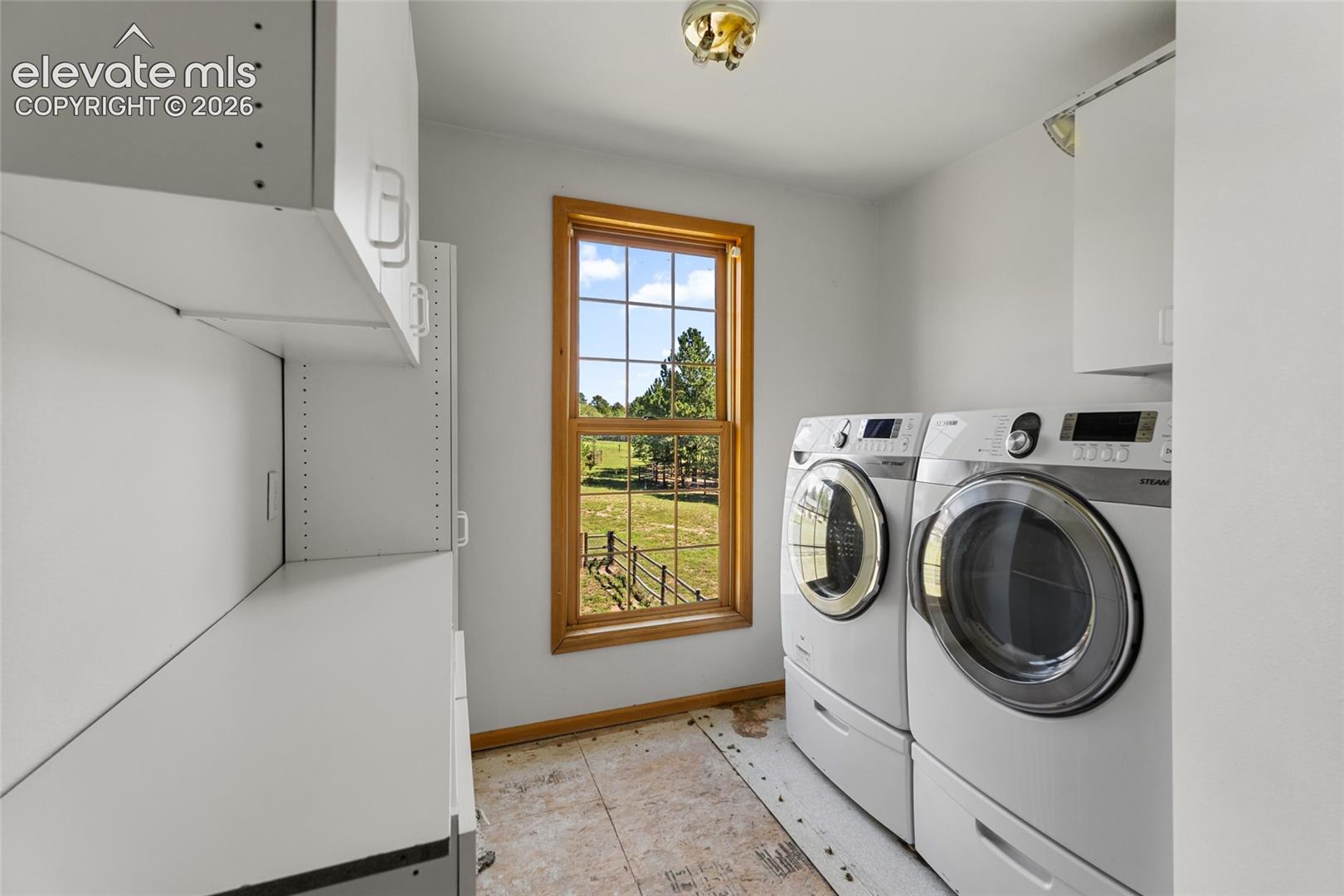 Laundry area featuring white cabinetry, a wood-framed window, and a flush mount ceiling light
