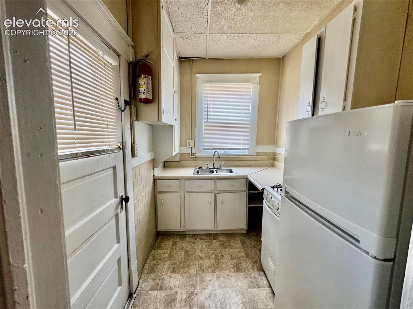 Kitchen featuring white cabinetry, a double basin sink, and a built-in refrigerator