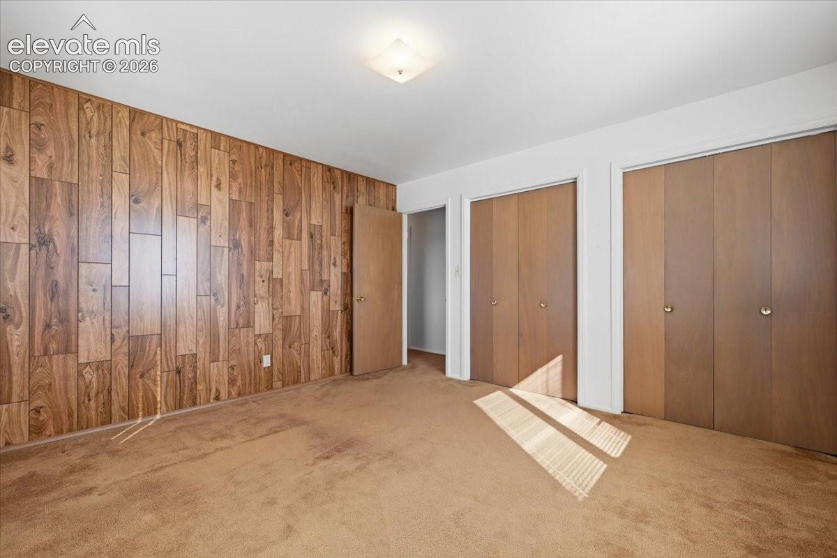 Wood-paneled accent wall, dual bi-fold door closets, and flush-mount ceiling lighting