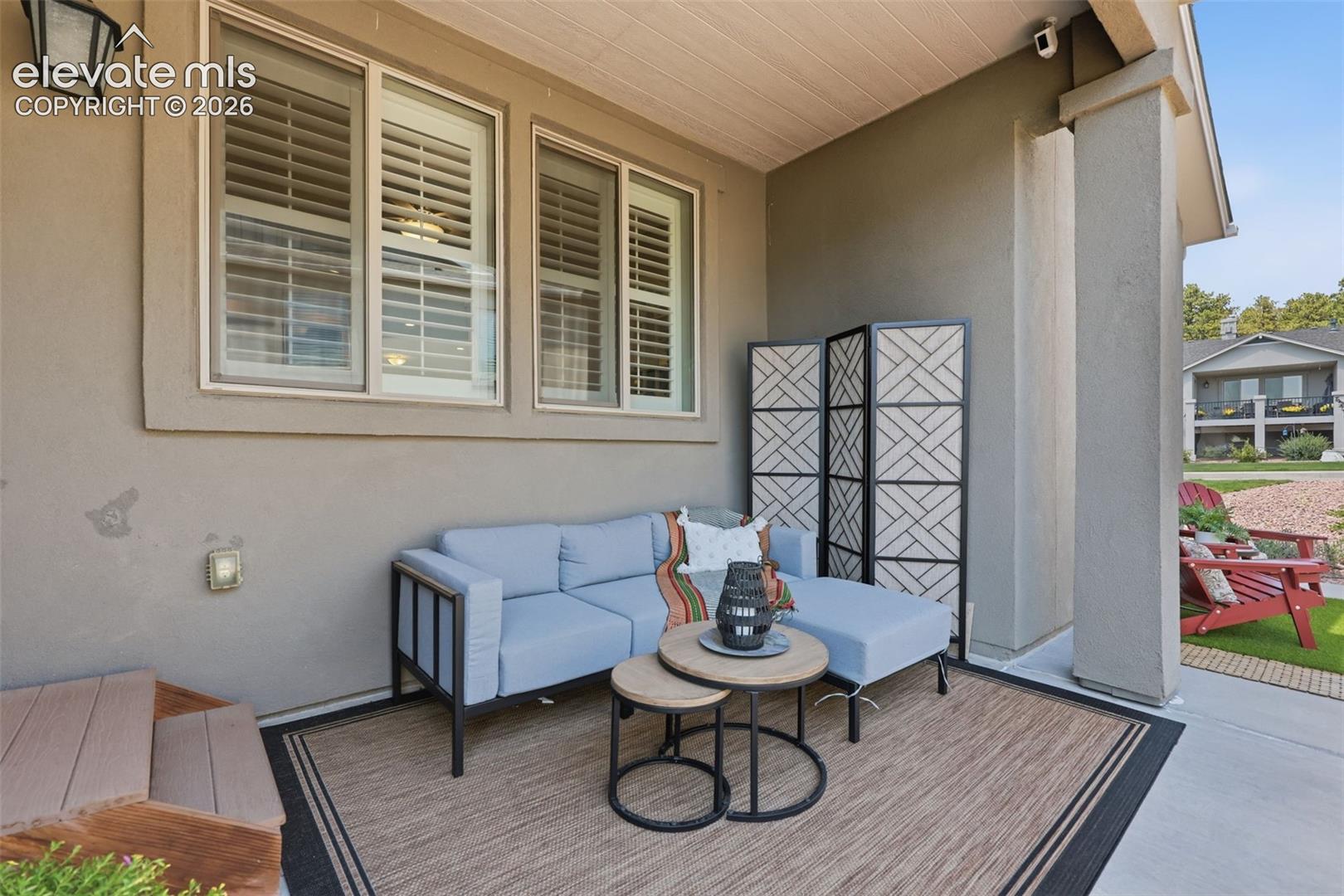 Covered outdoor patio with a stucco exterior and white window shutters.